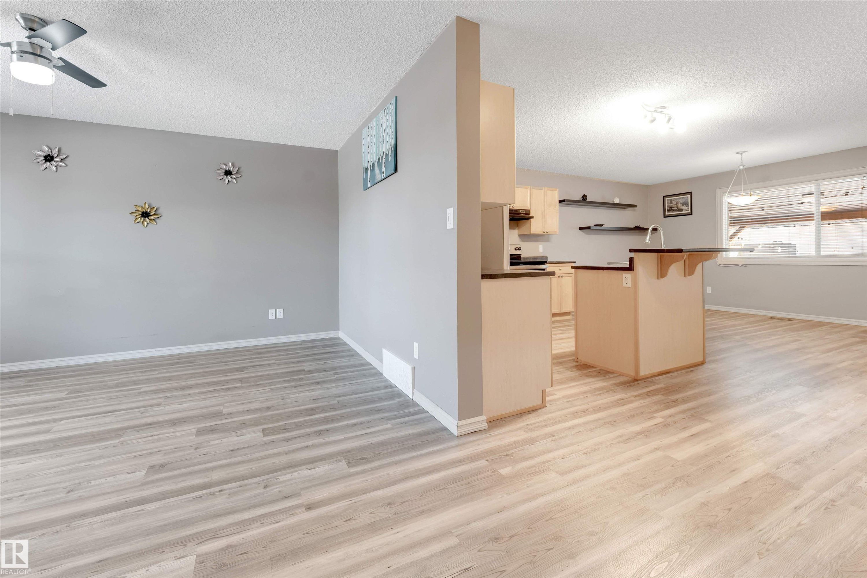 Kitchen with dark countertops, a breakfast bar, a ceiling fan, a textured ceiling, and a kitchen island - 1157 37 Avenue, Edmonton, AB - Indoor