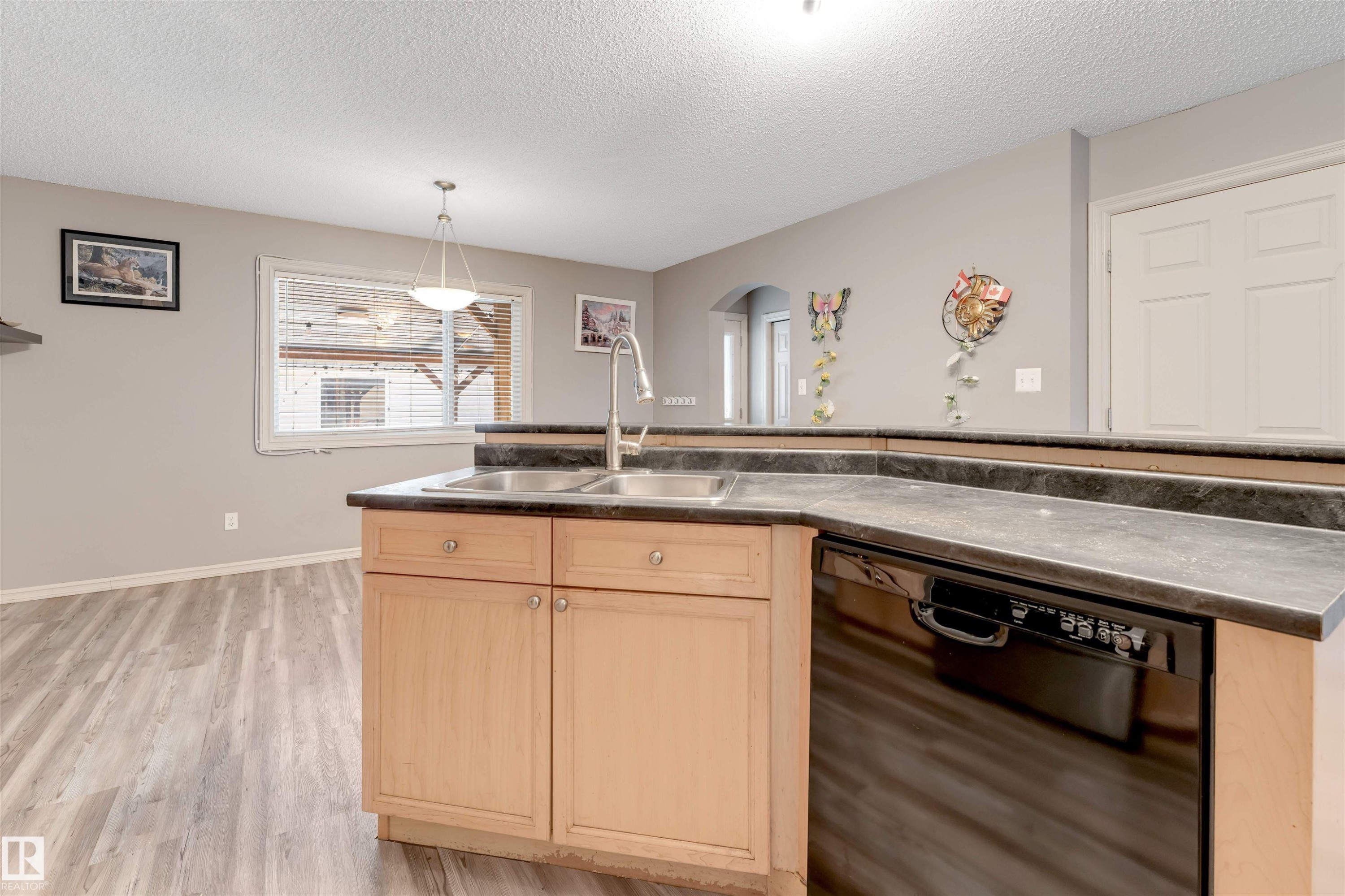 Kitchen with black dishwasher, light wood finish cabinets, dark countertops, light wood-style floors, and hanging light fixtures - 1157 37 Avenue, Edmonton, AB - Indoor Photo Showing Kitchen