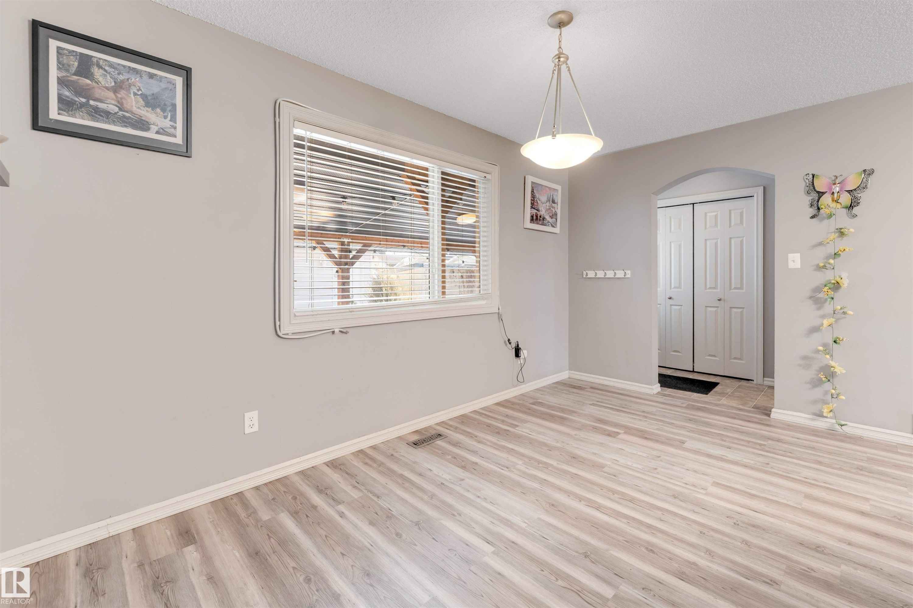 Unfurnished dining area featuring light wood finished floors, arched walkways, and a textured ceiling - 1157 37 Avenue, Edmonton, AB - Indoor Photo Showing Other Room