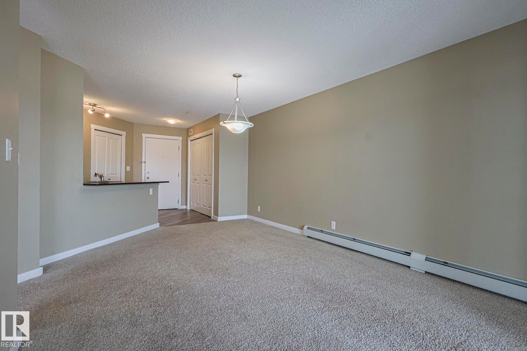 Spacious room featuring neutral carpeting, light-colored walls, and a ceiling-mounted light fixture - 313 1510 Watt Drive, Edmonton, AB - Indoor Photo Showing Other Room