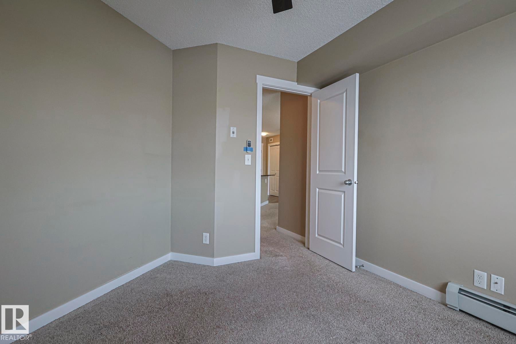 This room features neutral-toned walls, a textured ceiling, and carpeted flooring - 313 1510 Watt Drive, Edmonton, AB - Indoor Photo Showing Other Room