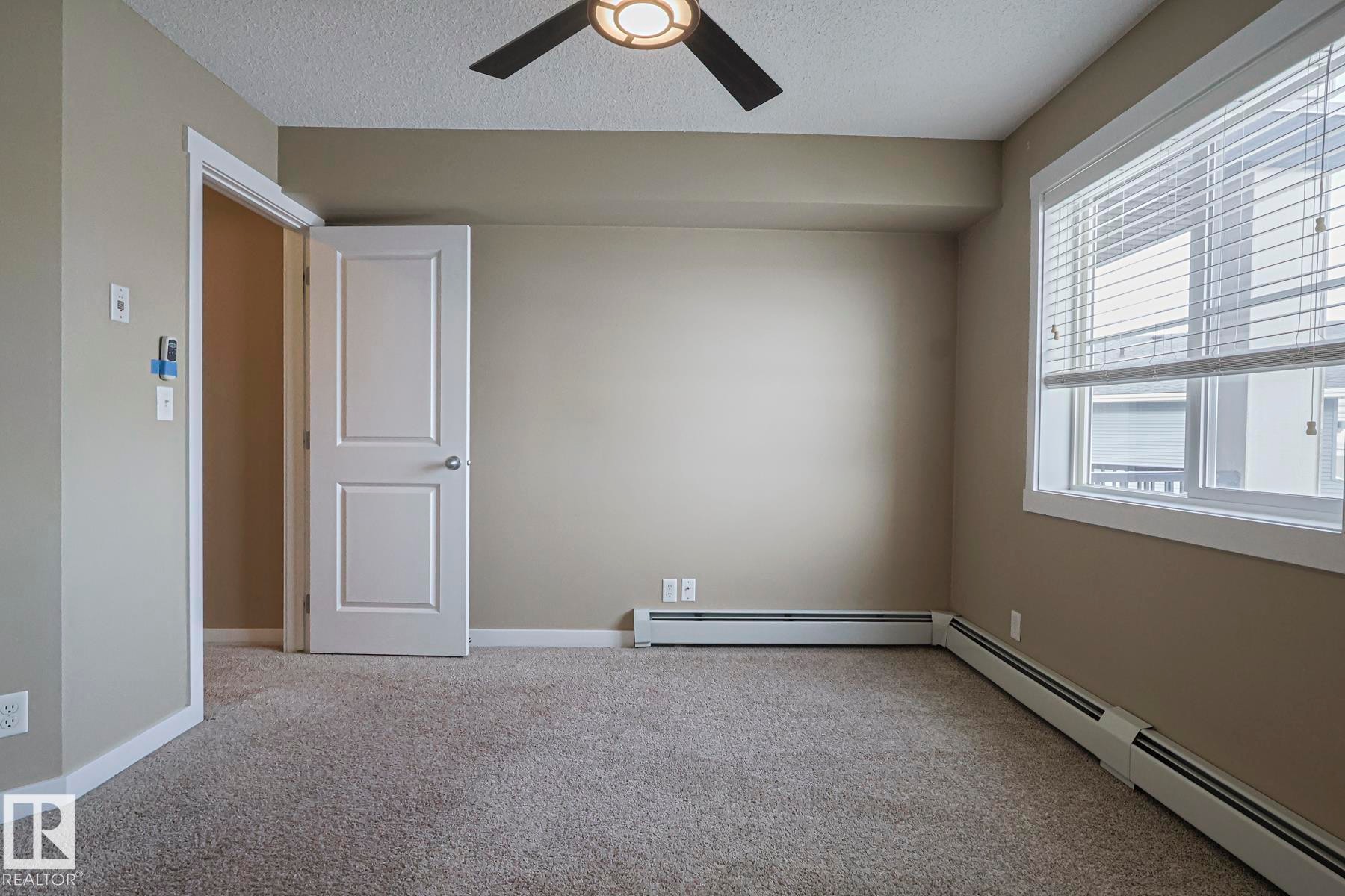 Room featuring carpeted flooring, a ceiling fan with integrated lighting, and a window with blinds - 313 1510 Watt Drive, Edmonton, AB - Indoor Photo Showing Other Room
