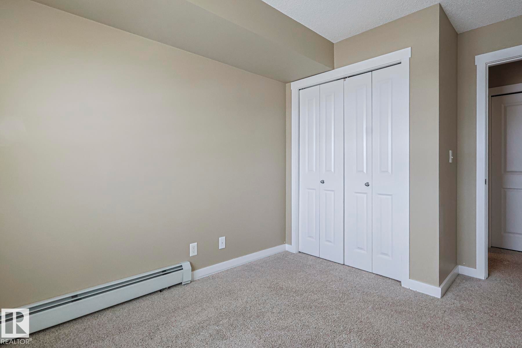 This room features light tan walls, a textured ceiling, and gray carpeted flooring - 313 1510 Watt Drive, Edmonton, AB - Indoor