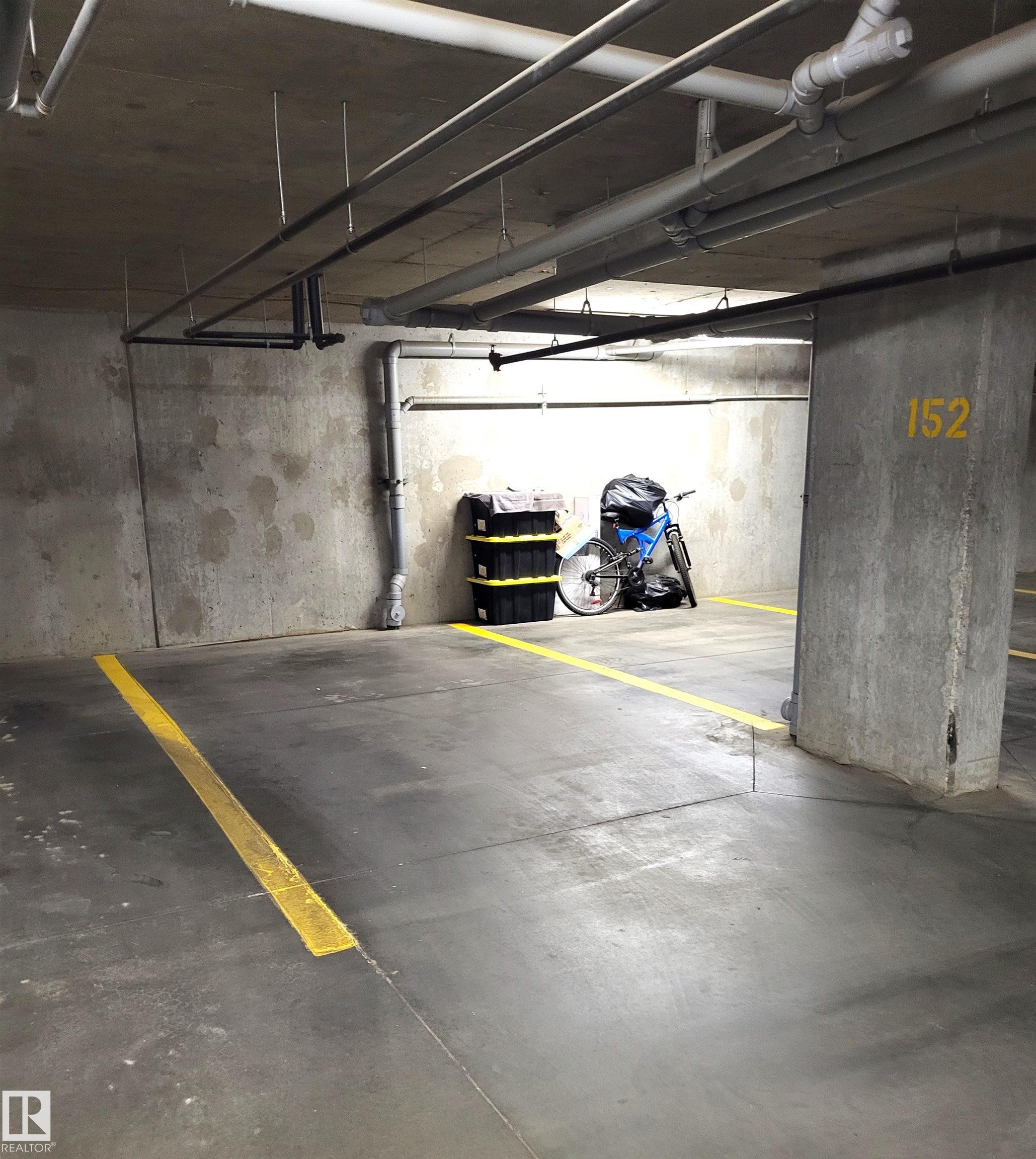 Designated parking space with clear yellow demarcation lines and an overhead concrete ceiling with visible piping - 313 1510 Watt Drive, Edmonton, AB - Indoor Photo Showing Garage