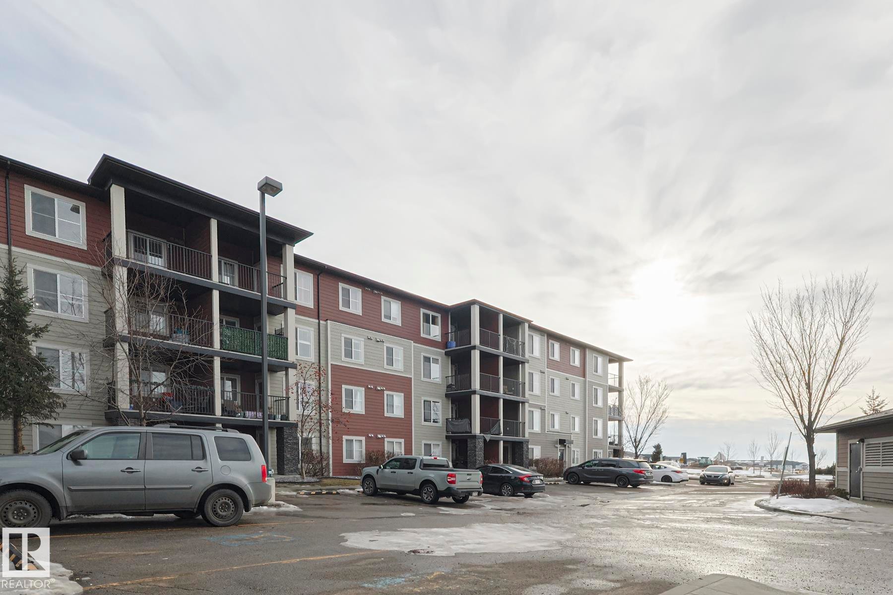 The property is a multi-story building featuring balconies with dark railings, a light-colored siding, and windows - 313 1510 Watt Drive, Edmonton, AB - Outdoor With Facade