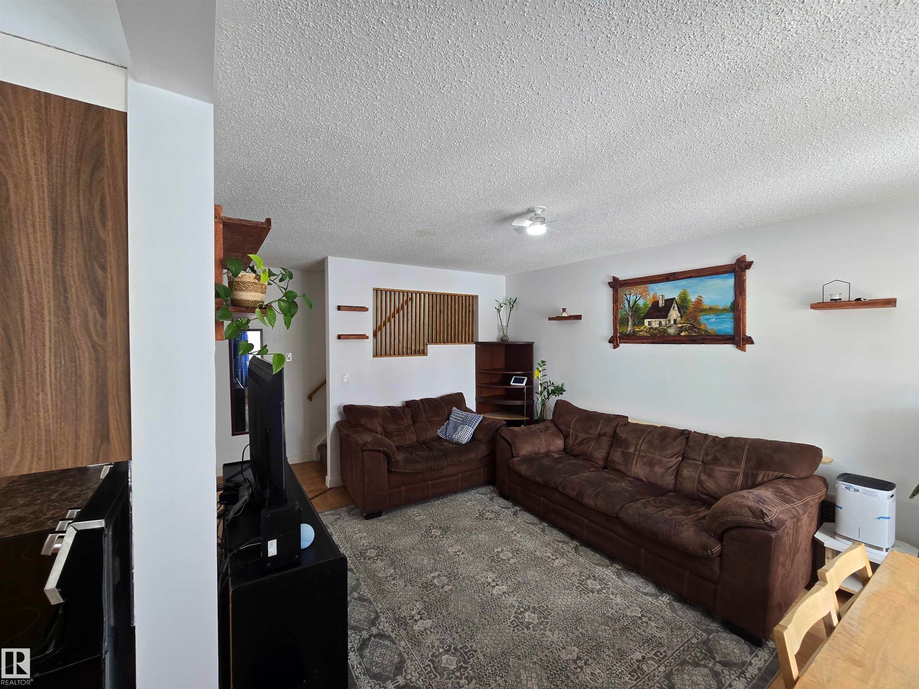 Spacious living area featuring white walls, a textured ceiling, and wood accents - 80 Amberly Crest, Edmonton, AB - Indoor Photo Showing Living Room