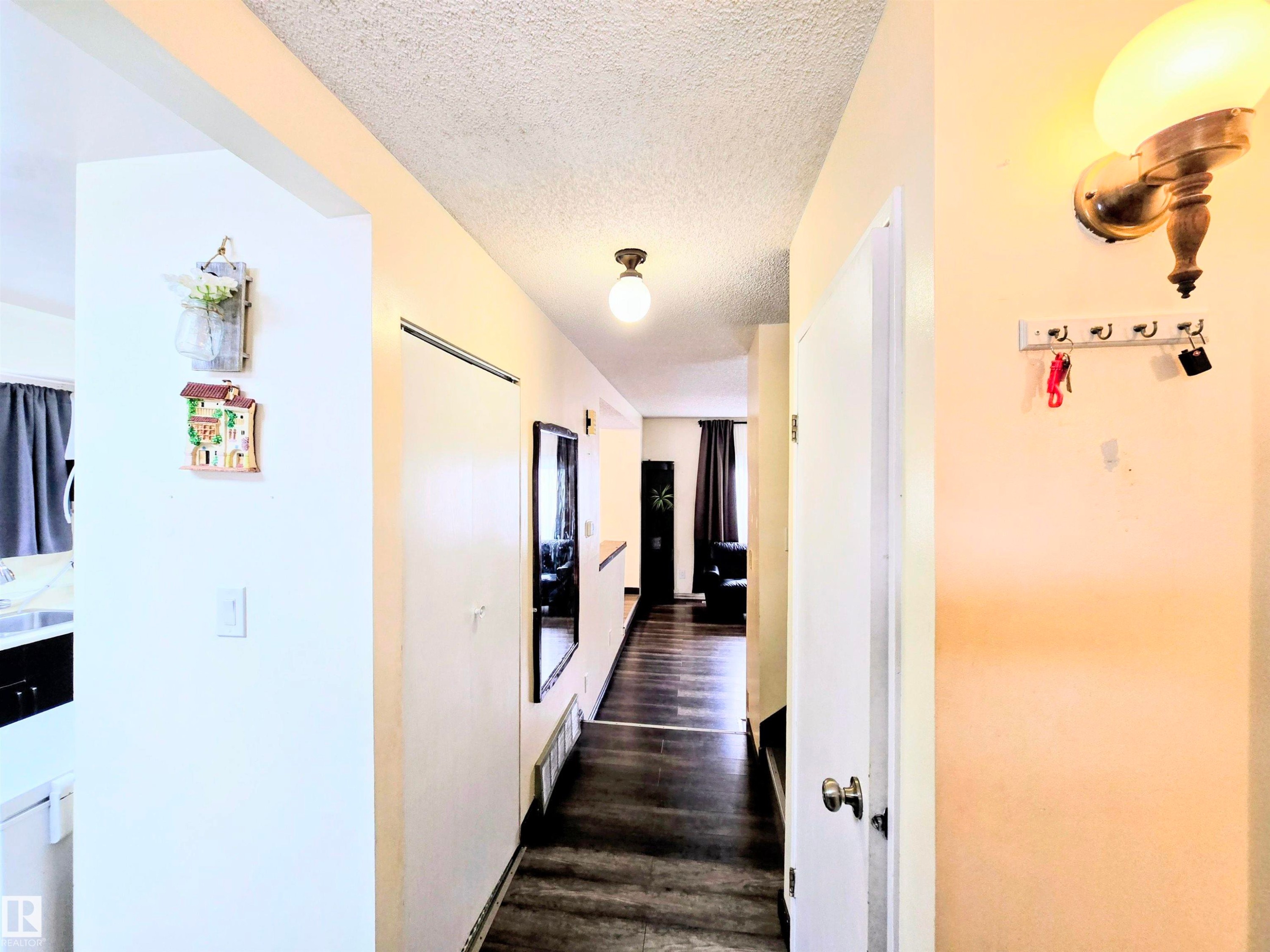 Hall featuring a textured ceiling, dark wood-style flooring, and washer / clothes dryer - 2 4403 Riverbend Road, Edmonton, AB - Indoor Photo Showing Other Room
