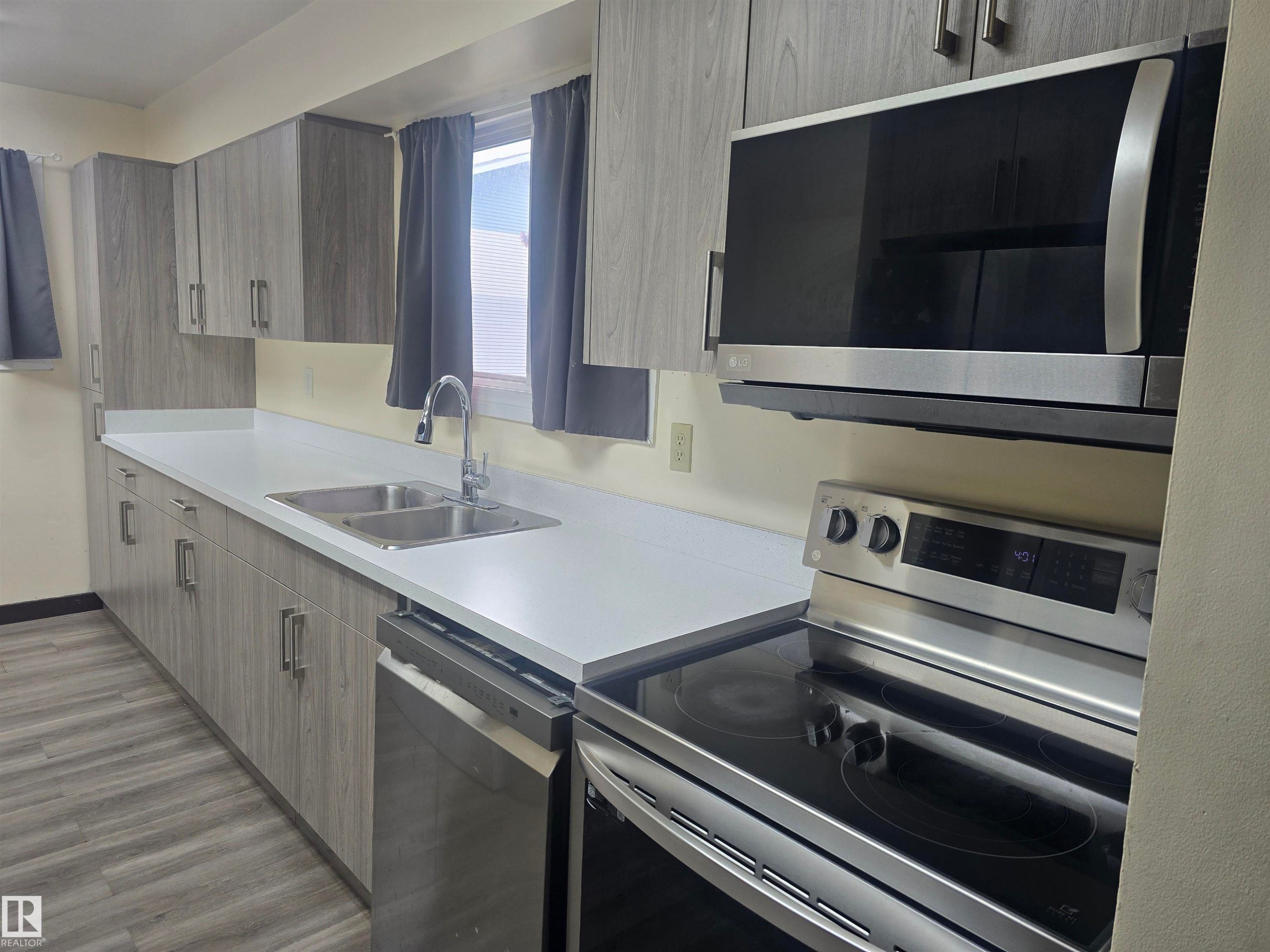 Kitchen featuring extensive gray wood-finish cabinetry, bright white countertops, and wood-finish flooring - 2 4403 Riverbend Road, Edmonton, AB