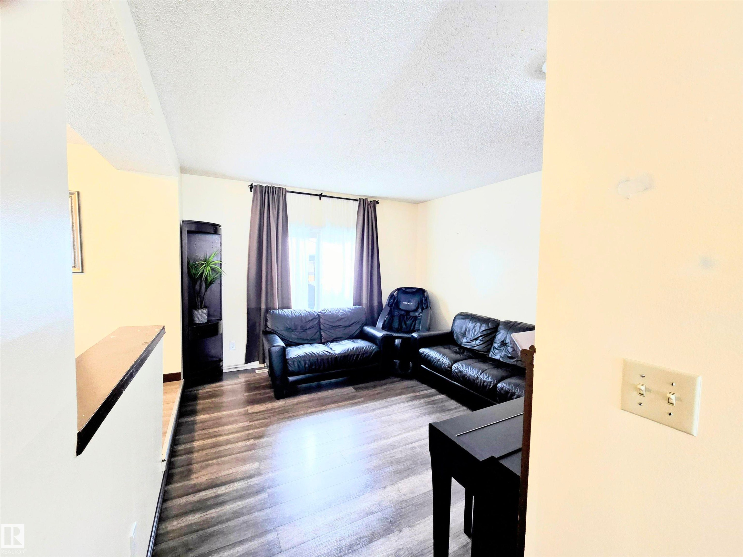 Living room with a textured ceiling and dark wood finished floors - 2 4403 Riverbend Road, Edmonton, AB - Indoor Photo Showing Living Room