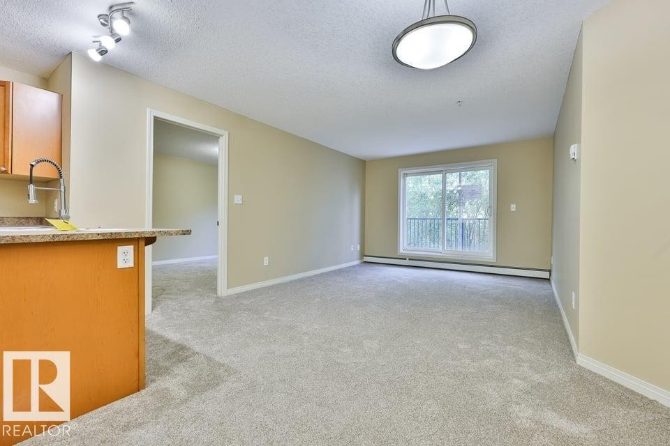 Living area featuring light-toned carpeting and neutral wall paint - #107 4903 47 Av, Stony Plain, AB - Indoor Photo Showing Other Room