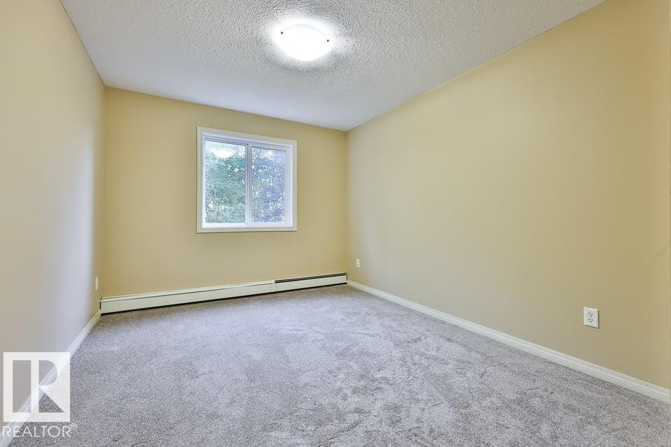 Room featuring neutral-toned walls, light grey carpeting, and a white window frame - #107 4903 47 Av, Stony Plain, AB - Indoor Photo Showing Other Room