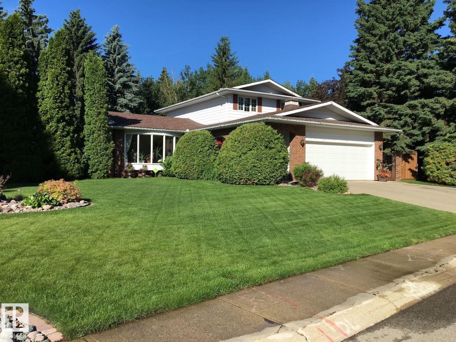 View of front of property with an attached garage, a front lawn, driveway, and brick siding - 206 Wolf Willow Crescent, Edmonton, AB - Outdoor