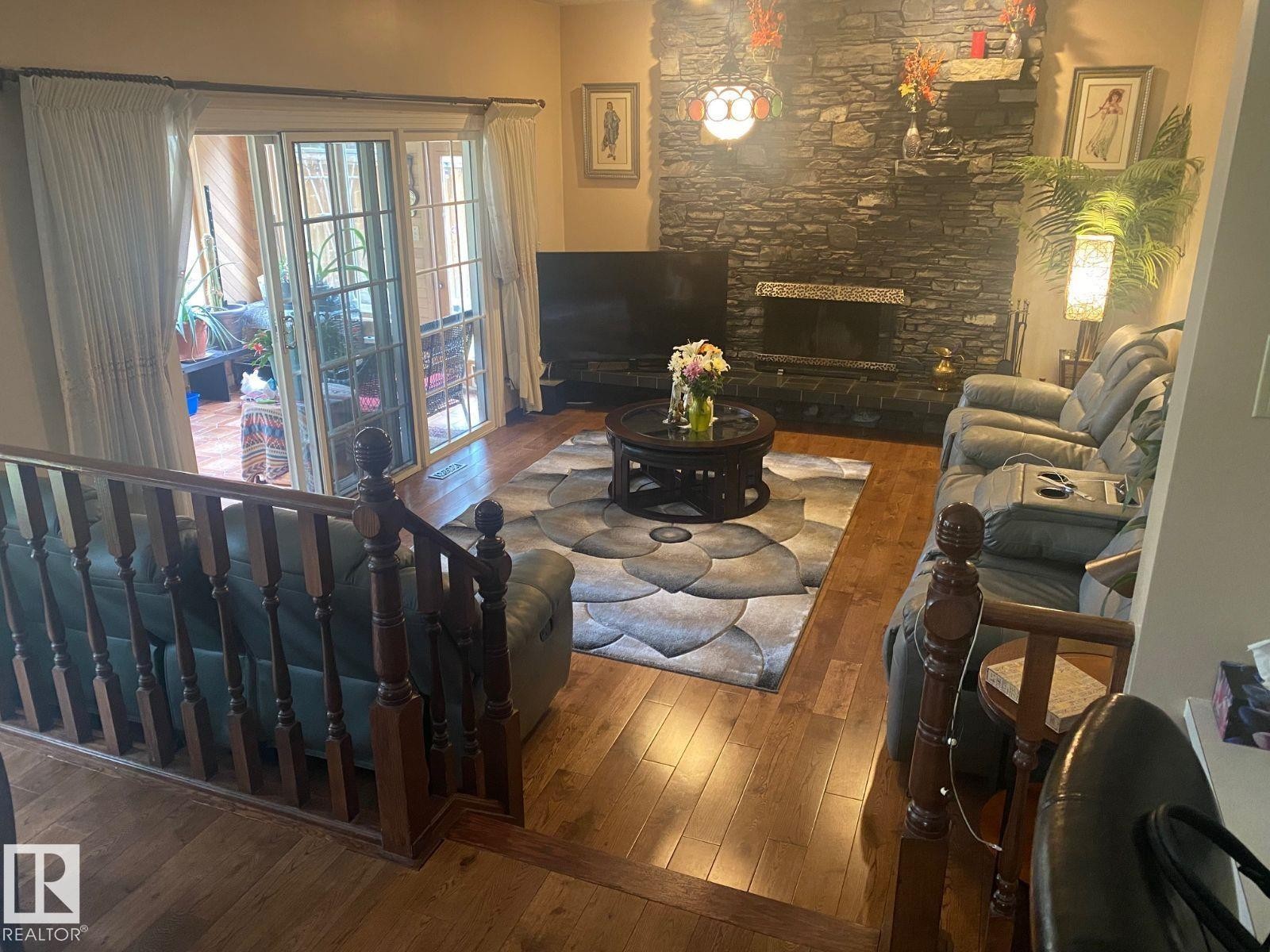 Living area with hardwood / wood-style flooring and a stone fireplace - 206 Wolf Willow Crescent, Edmonton, AB - Indoor With Fireplace