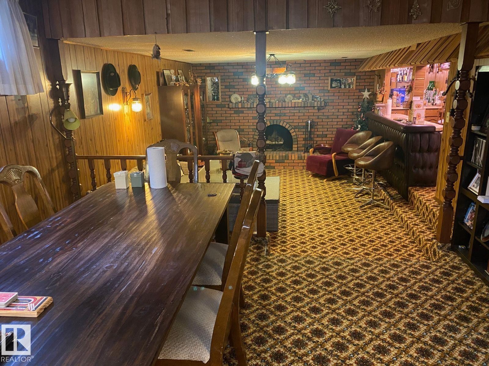 Dining space with wood walls, a brick fireplace, and brick wall - 206 Wolf Willow Crescent, Edmonton, AB - Indoor Photo Showing Dining Room