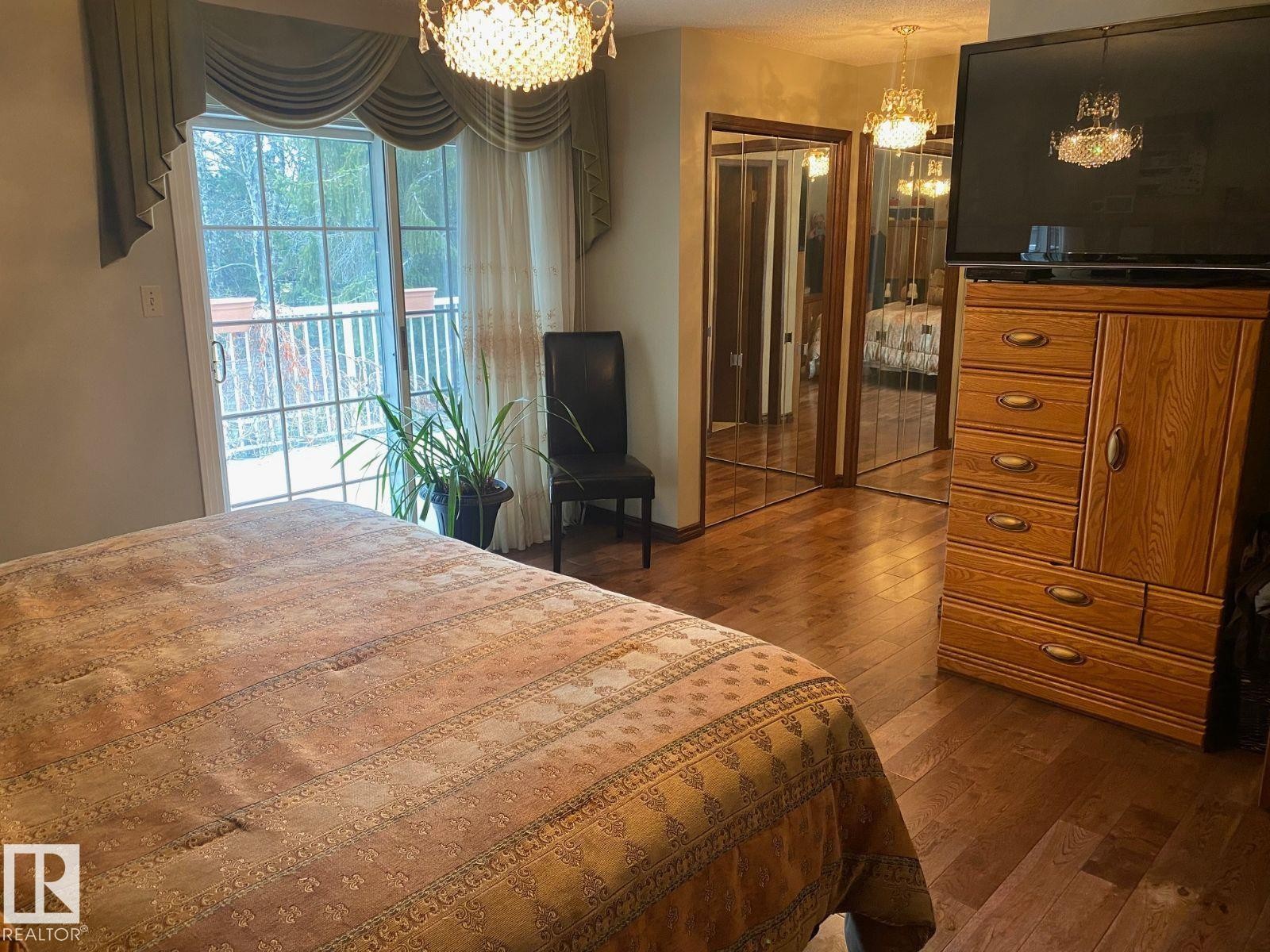 Bedroom with suspended lighting, a closet, dark wood finished floors, and access to outside - 206 Wolf Willow Crescent, Edmonton, AB - Indoor Photo Showing Bedroom