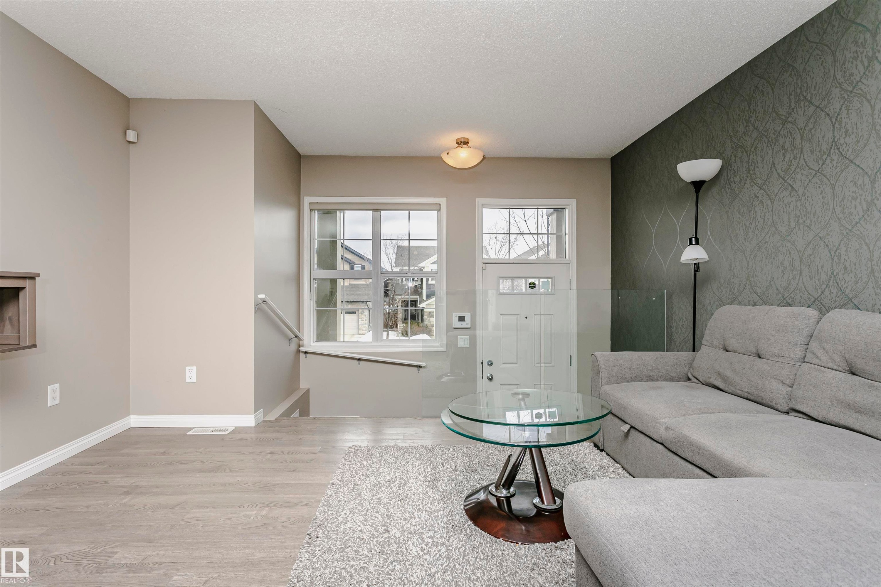 Living area featuring an accent wall, light wood-style floors, and wallpapered walls - 4011 Orchards Drive, Edmonton, AB - Indoor Photo Showing Living Room