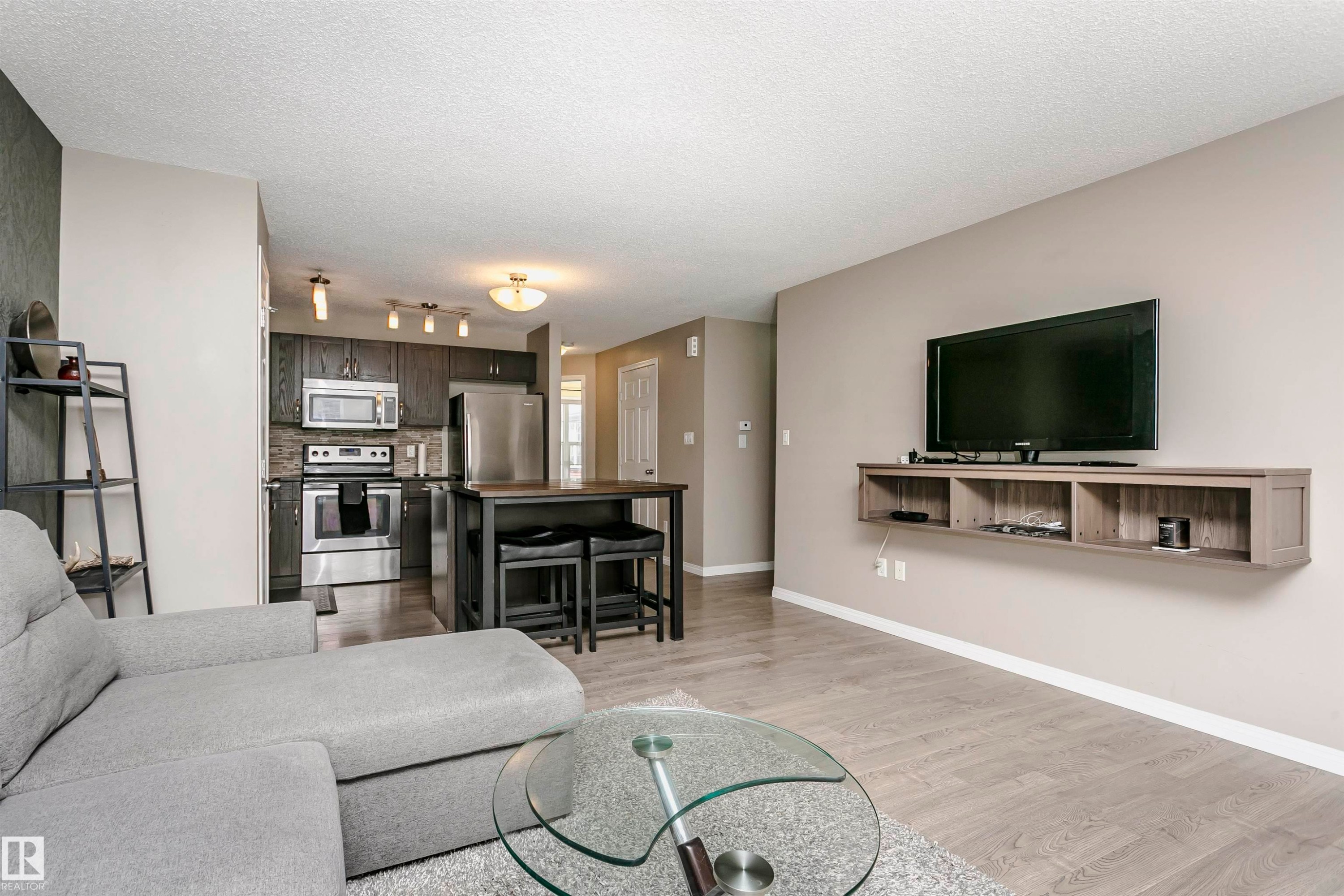 Living area with light wood-style flooring and a textured ceiling - 4011 Orchards Drive, Edmonton, AB - Indoor Photo Showing Living Room