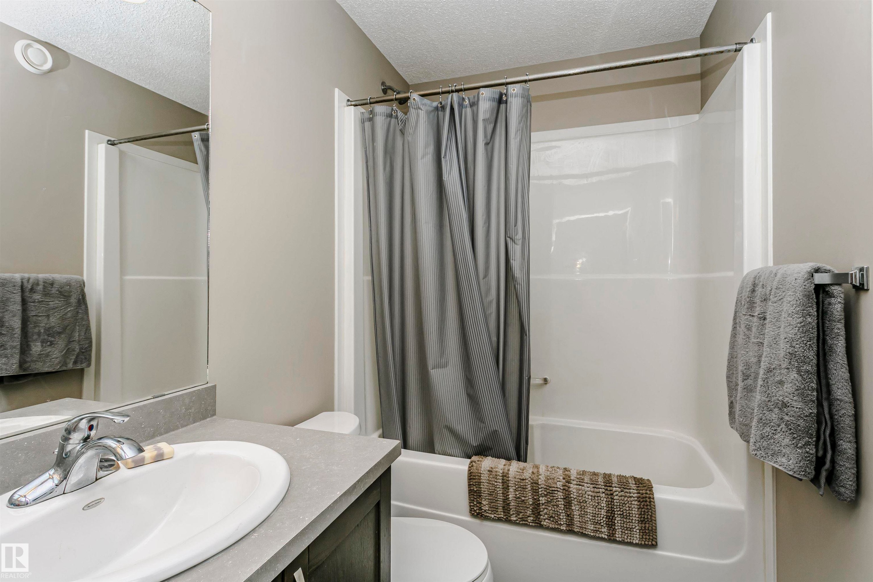 Bathroom featuring a textured ceiling, vanity, and shower / tub combo - 4011 Orchards Drive, Edmonton, AB - Indoor Photo Showing Bathroom