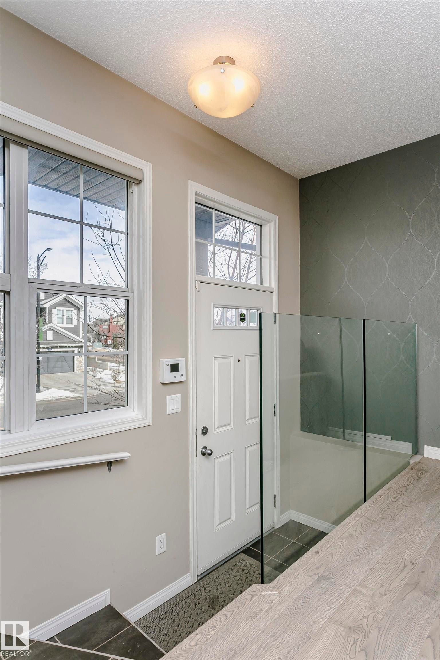 Entryway with dark tile patterned flooring and a textured ceiling - 4011 Orchards Drive, Edmonton, AB - Indoor