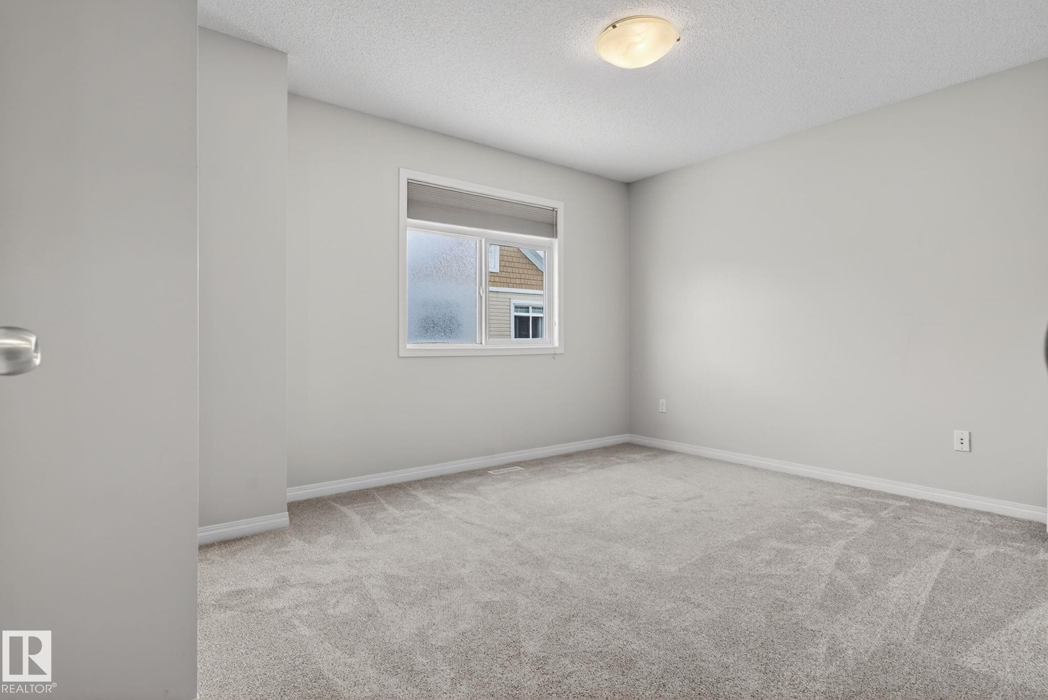 Spare room with light colored carpet and a textured ceiling - 60 1804 70 Street, Edmonton, AB - Indoor Photo Showing Other Room