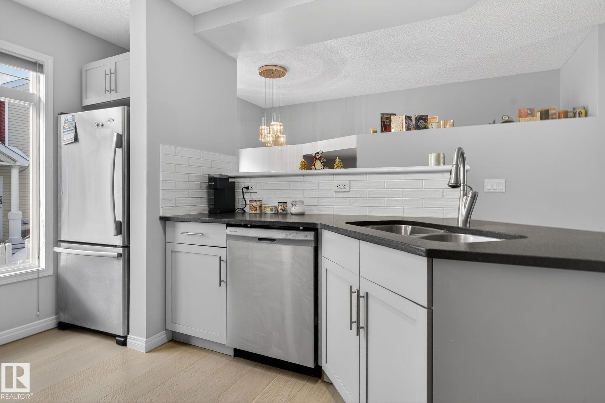Kitchen with stainless steel appliances, white cabinets, dark stone countertops, decorative backsplash, and light wood finished floors - 60 1804 70 Street, Edmonton, AB - Indoor Photo Showing Kitchen With Double Sink