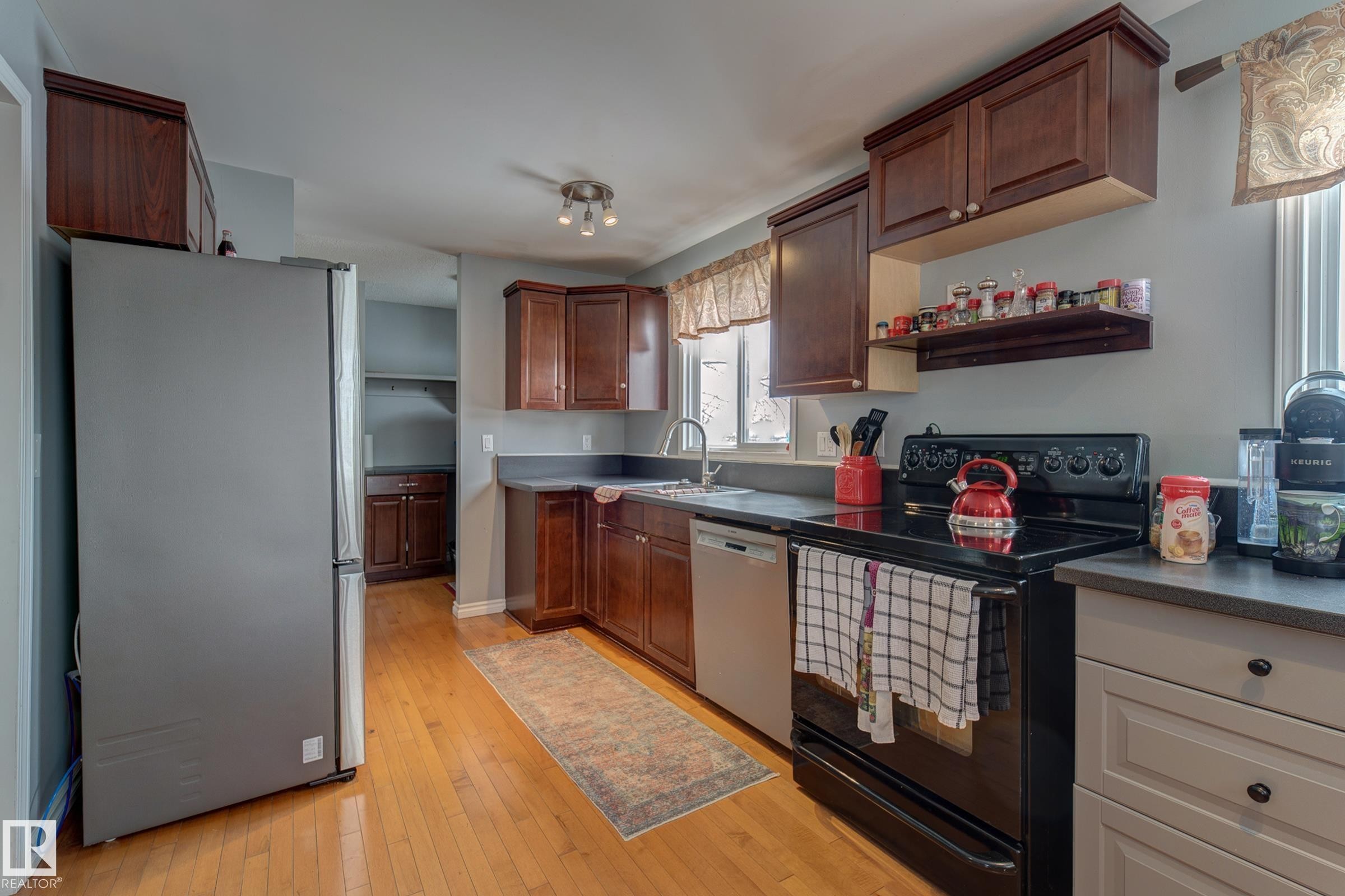 Kitchen with stainless steel appliances, light wood-style floors, and dark countertops - 4823 10 Avenue, Edmonton, AB - Indoor Photo Showing Kitchen