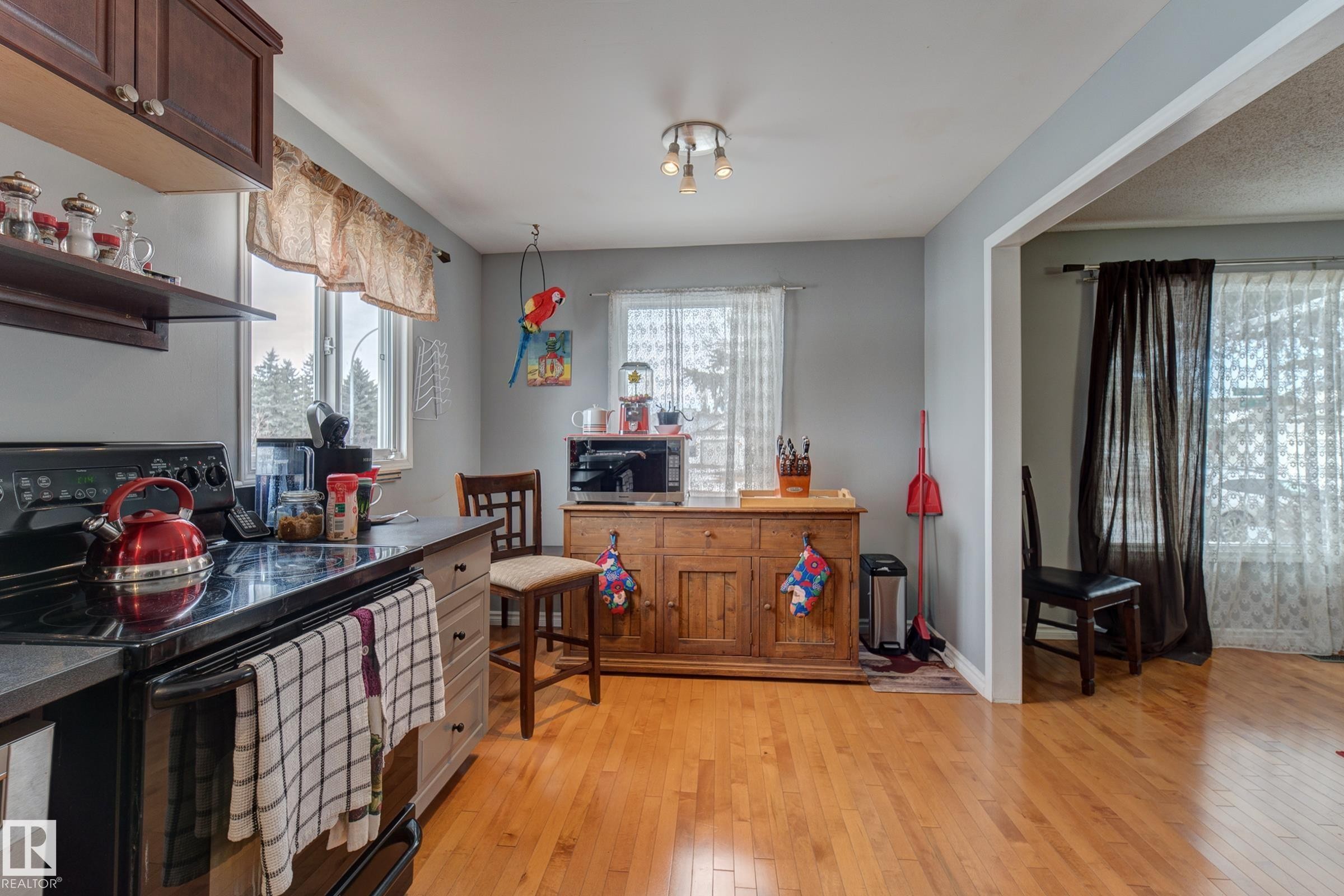 Kitchen with black electric range oven, light wood finished floors, stainless steel microwave, and dark countertops - 4823 10 Avenue, Edmonton, AB - Indoor