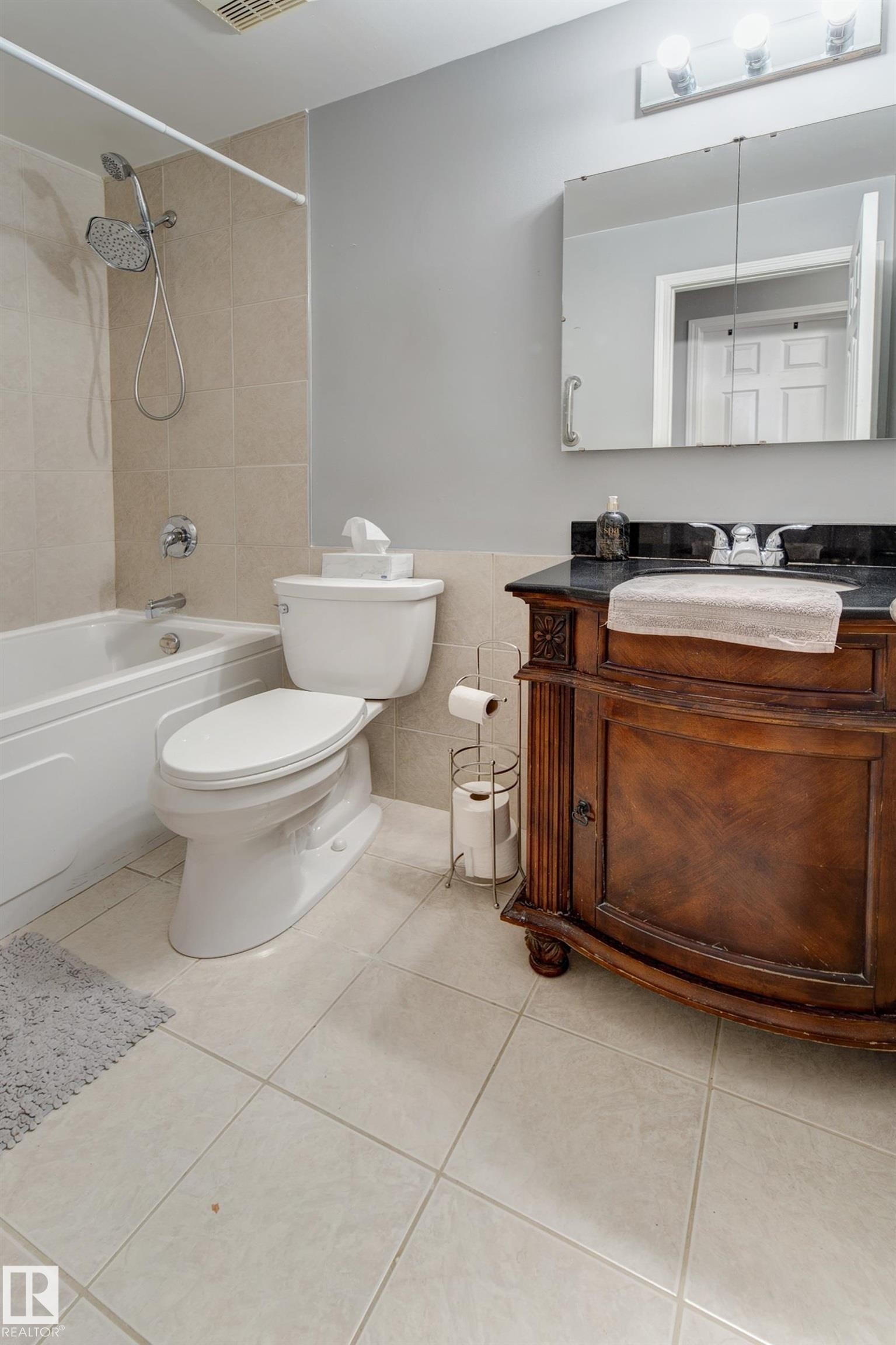Full bathroom featuring vanity, shower / tub combination, tile walls, light tile patterned floors, and a wainscoted wall - 4823 10 Avenue, Edmonton, AB - Indoor Photo Showing Bathroom