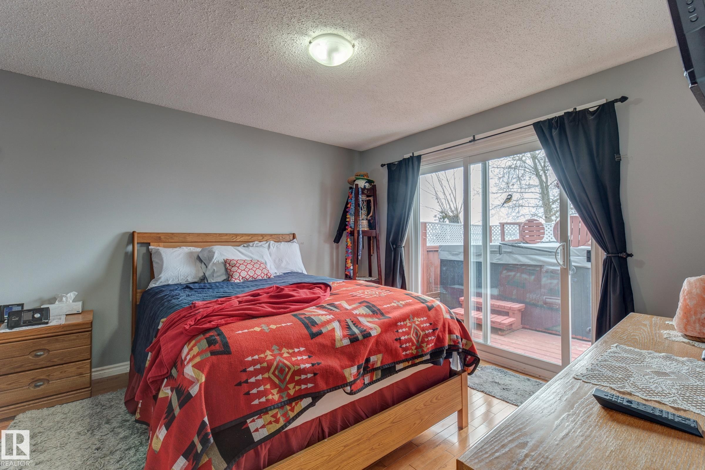 Bedroom with access to exterior, a textured ceiling, and light wood finished floors - 4823 10 Avenue, Edmonton, AB - Indoor Photo Showing Bedroom