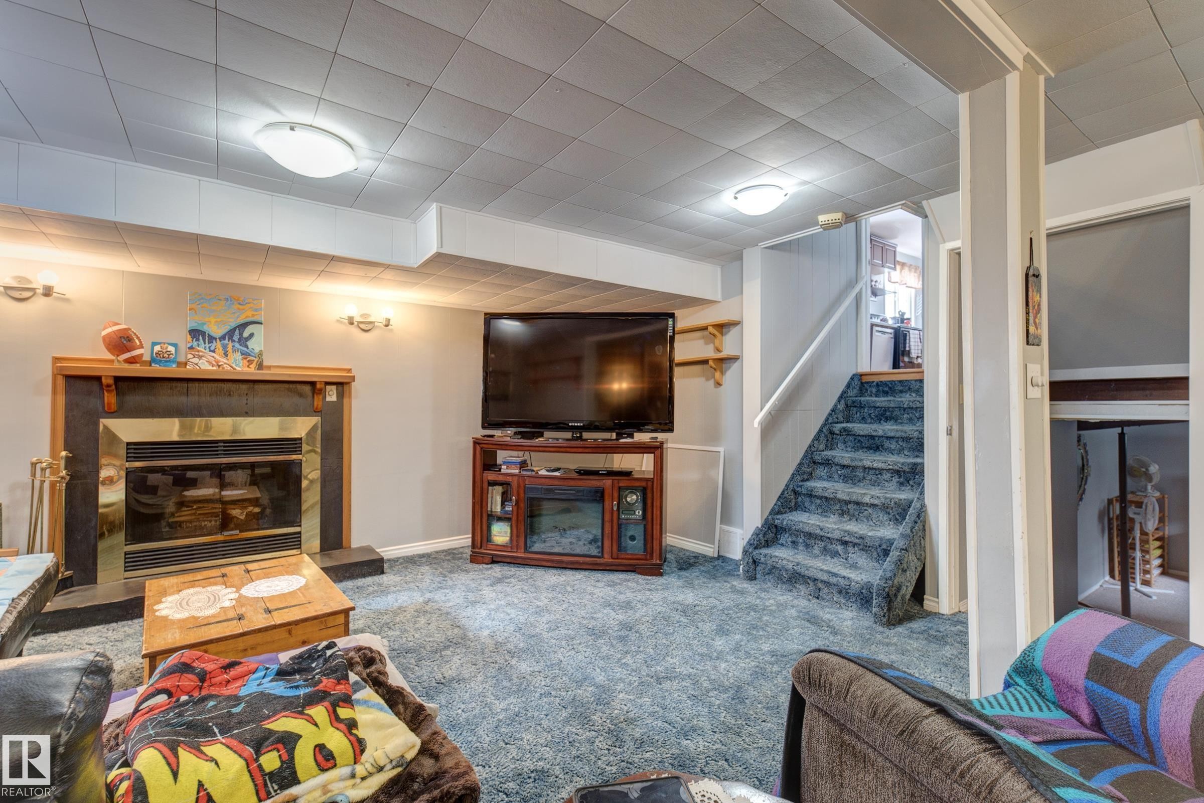 Living room with a glass covered fireplace and carpet floors - 4823 10 Avenue, Edmonton, AB - Indoor Photo Showing Living Room With Fireplace