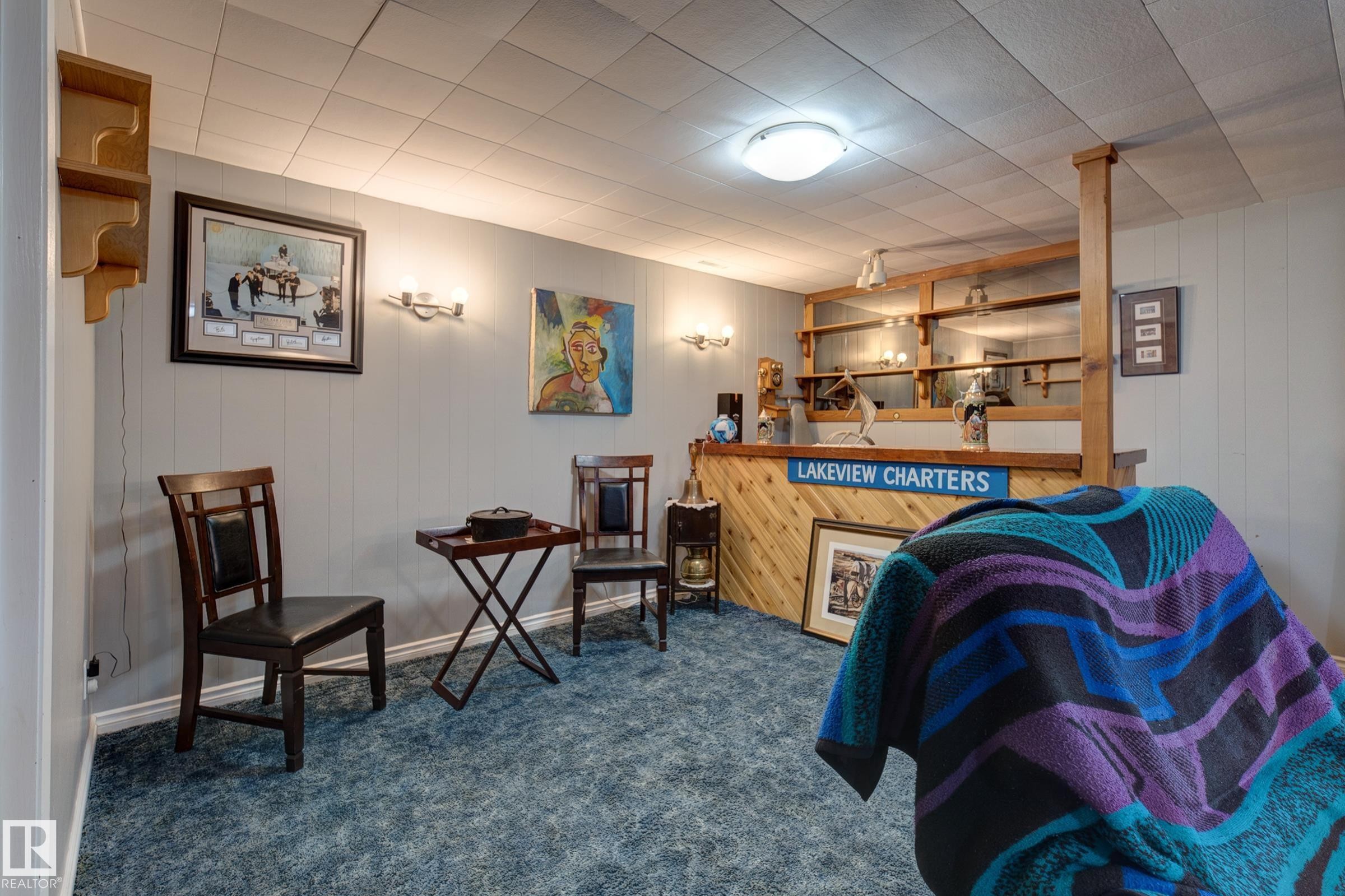 Sitting room featuring dark colored carpet and wood walls - 4823 10 Avenue, Edmonton, AB - Indoor