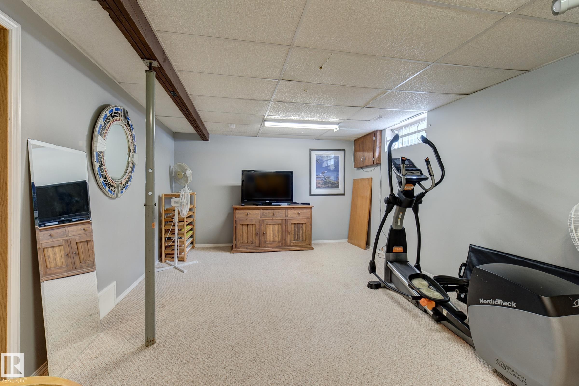 Workout room featuring a drop ceiling and light colored carpet - 4823 10 Avenue, Edmonton, AB - Indoor Photo Showing Gym Room