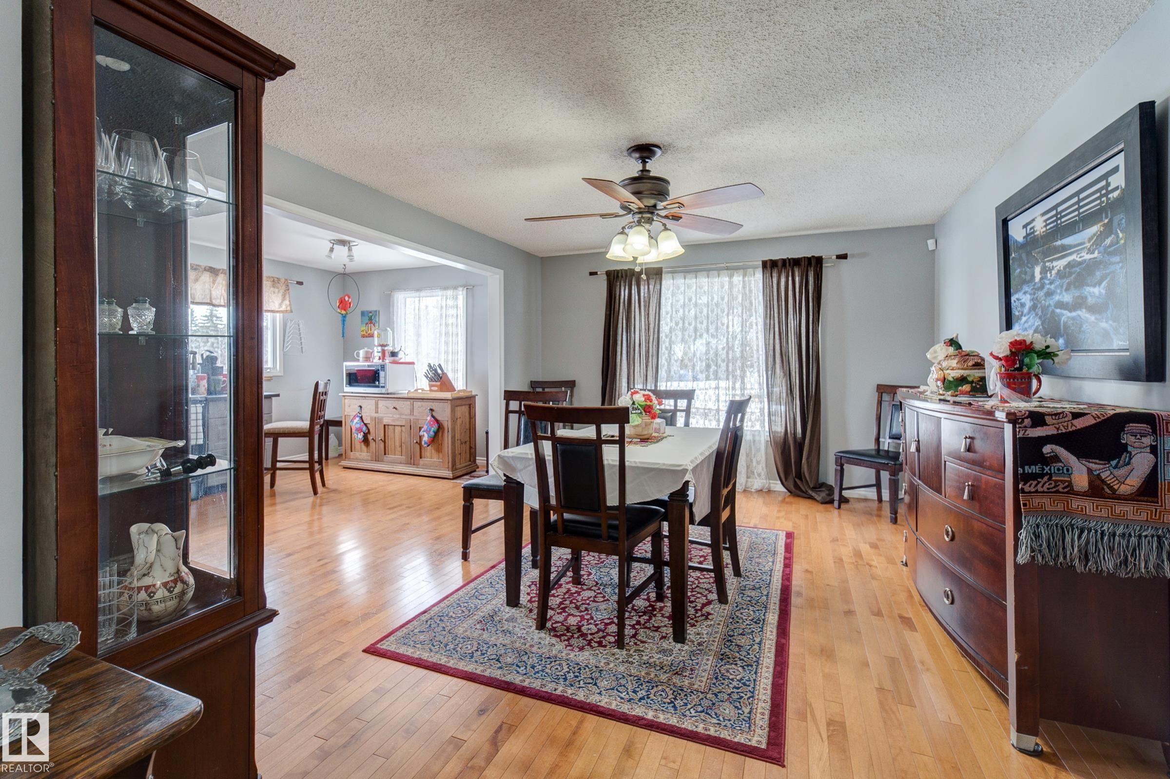 Dining area with light wood-style flooring, a textured ceiling, and a ceiling fan - 4823 10 Avenue, Edmonton, AB - Indoor Photo Showing Dining Room
