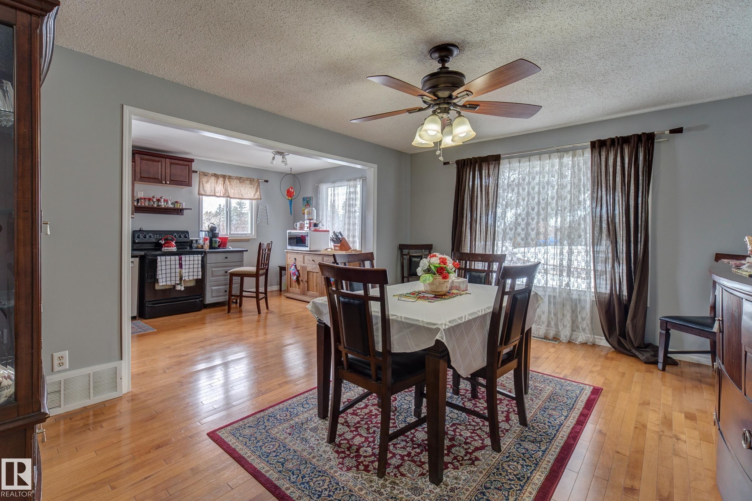 Dining area with light wood-type flooring, a textured ceiling, and a ceiling fan - 4823 10 Avenue, Edmonton, AB - Indoor Photo Showing Dining Room