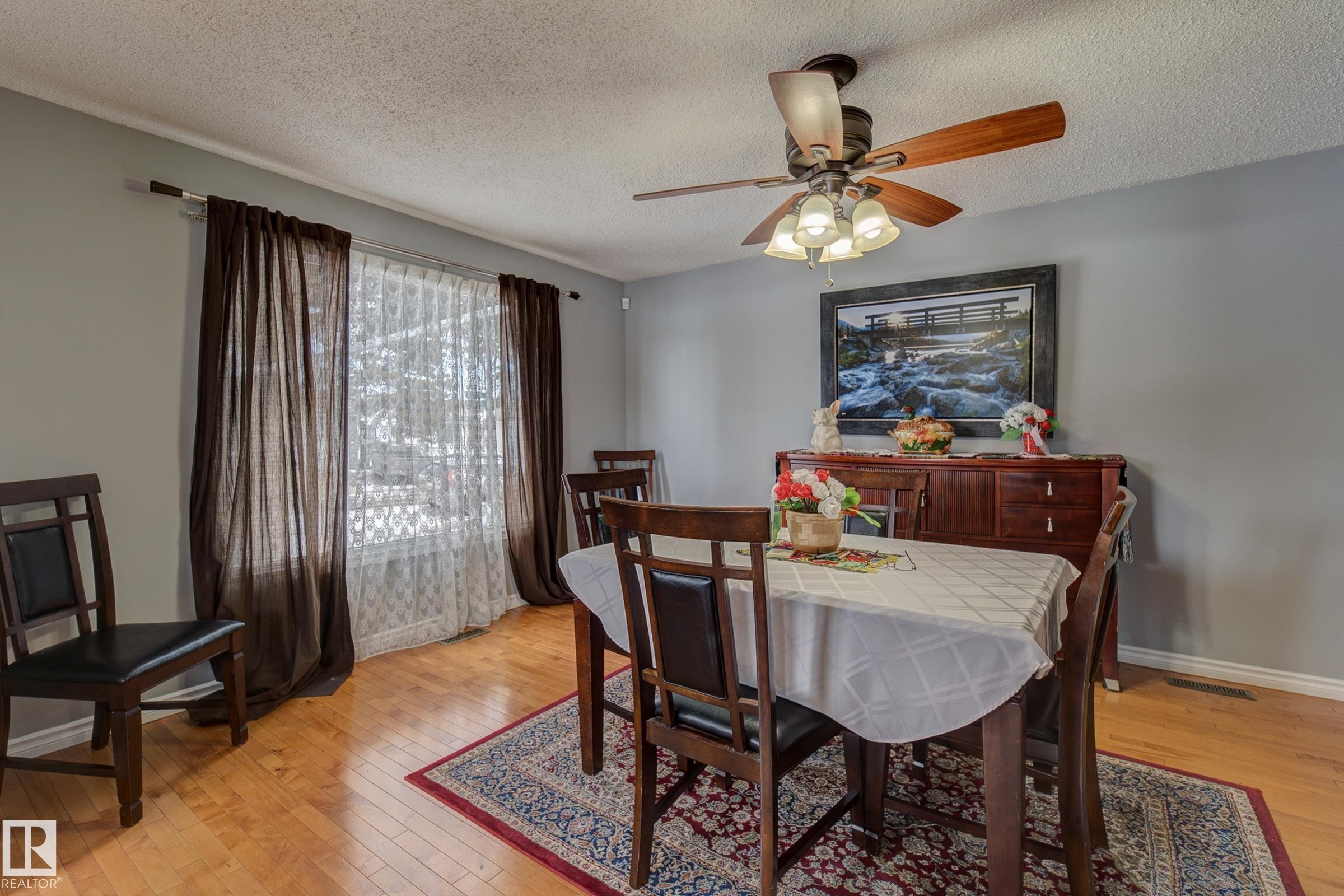 Dining area with light wood-style flooring, ceiling fan, and a textured ceiling - 4823 10 Avenue, Edmonton, AB - Indoor Photo Showing Dining Room