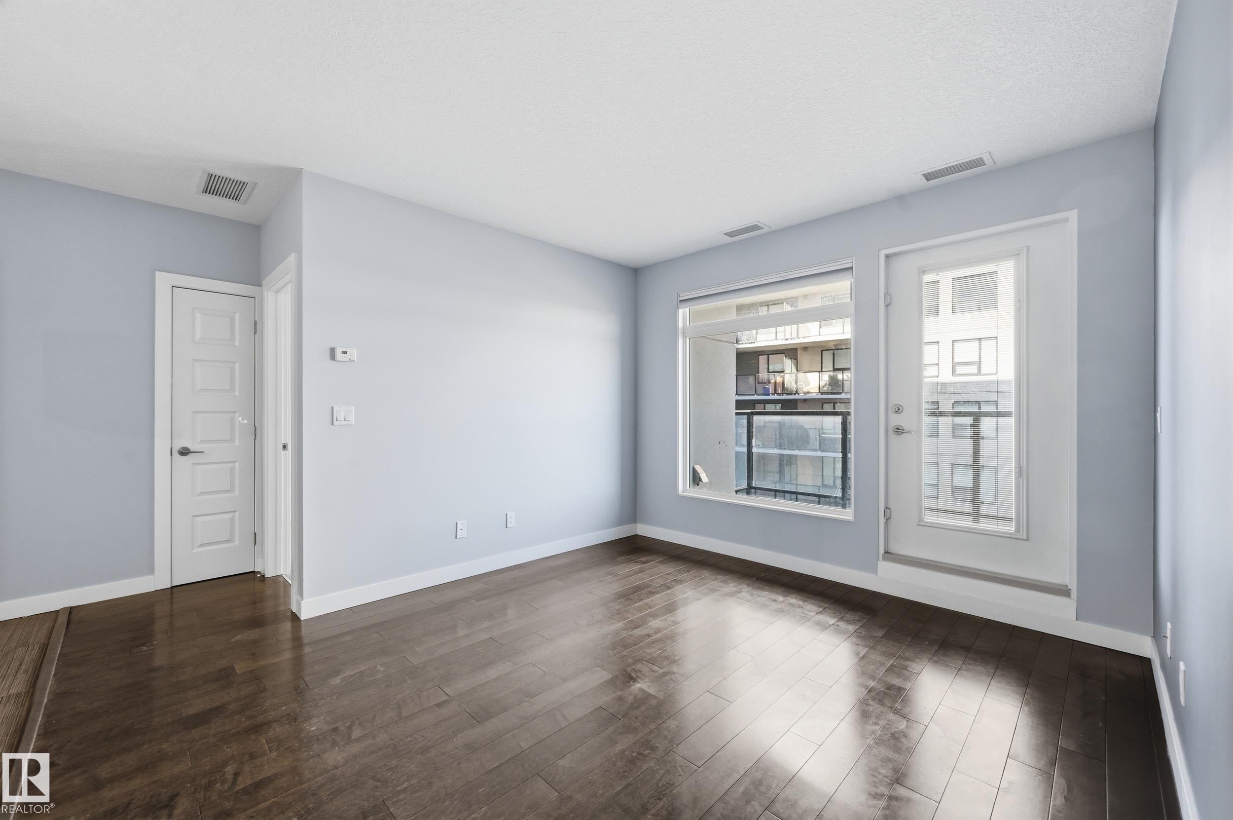 Spare room with dark wood-type flooring and baseboards - 511 5151 Windermere Boulevard, Edmonton, AB - Indoor Photo Showing Other Room