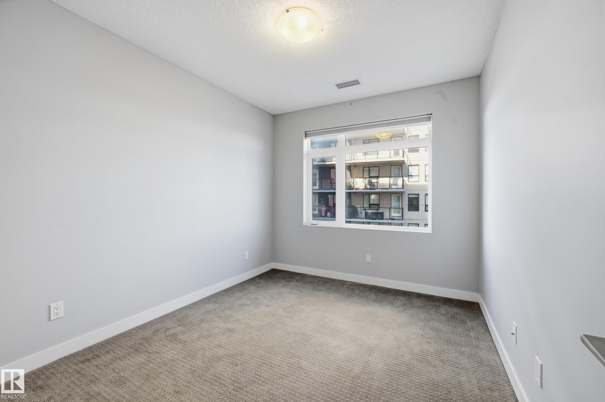 Unfurnished room featuring light colored carpet and a textured ceiling - 511 5151 Windermere Boulevard, Edmonton, AB - Indoor Photo Showing Other Room