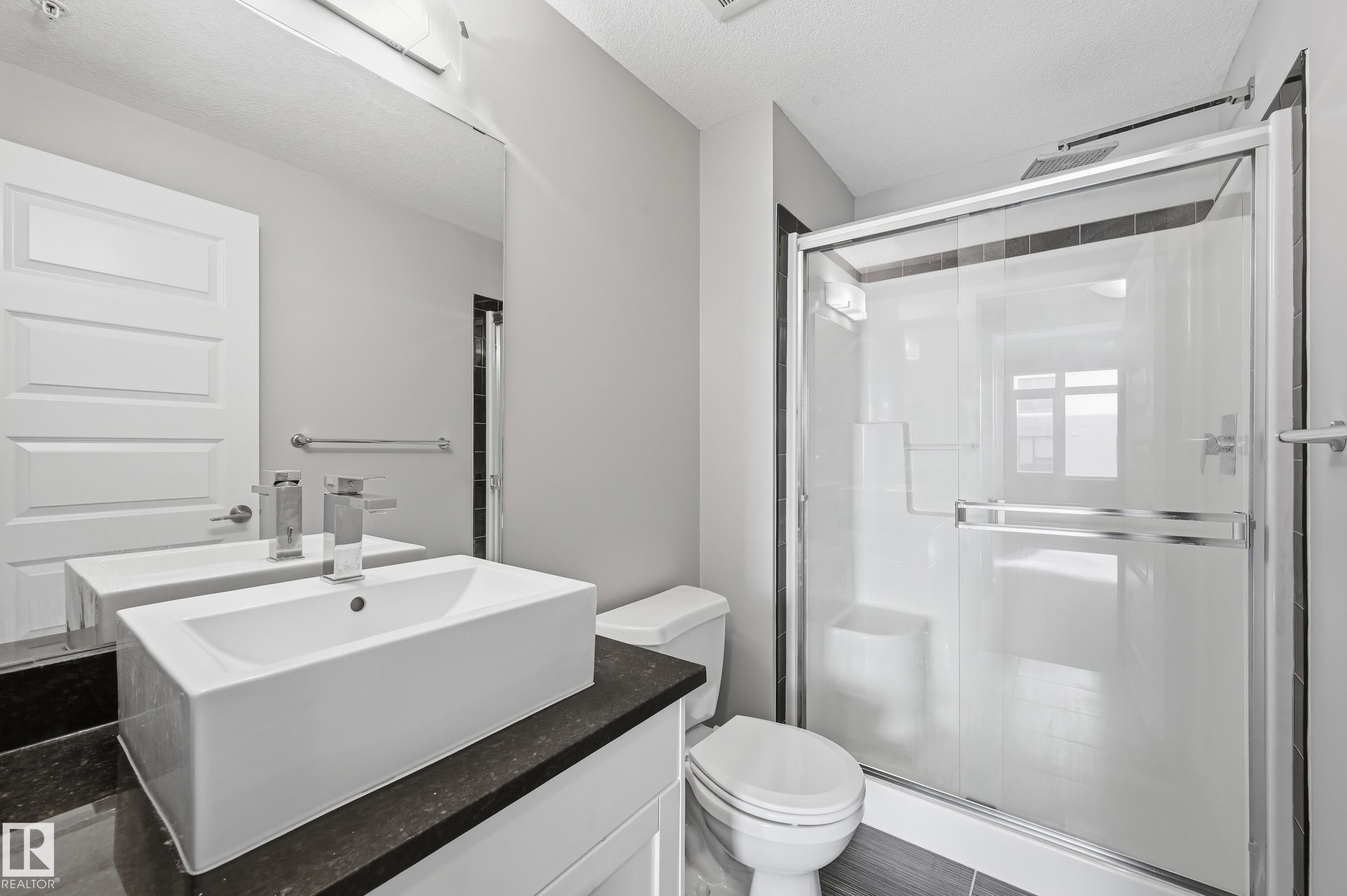 Bathroom featuring a stall shower, vanity, and a textured ceiling - 511 5151 Windermere Boulevard, Edmonton, AB - Indoor Photo Showing Bathroom