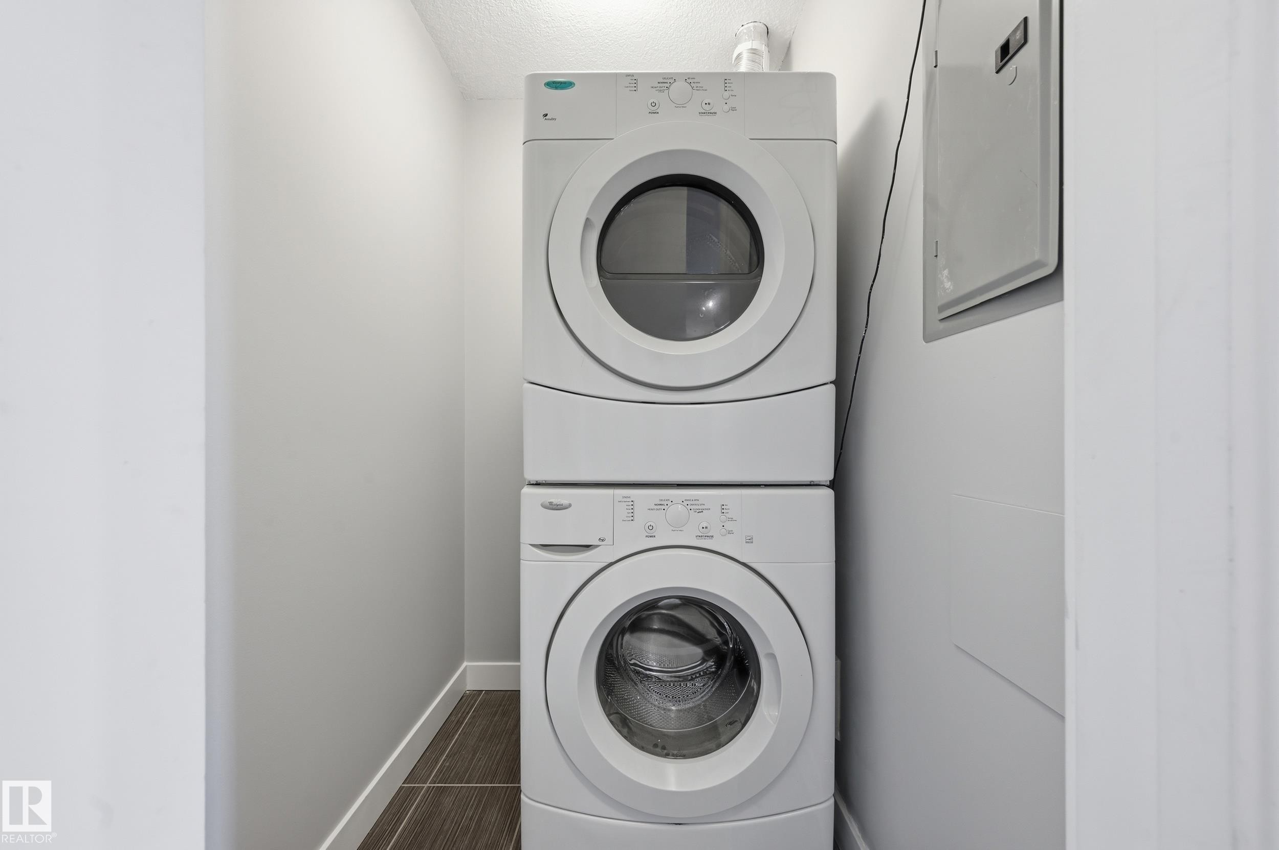 Laundry area featuring electric panel and stacked washer and clothes dryer - 511 5151 Windermere Boulevard, Edmonton, AB - Indoor Photo Showing Laundry Room
