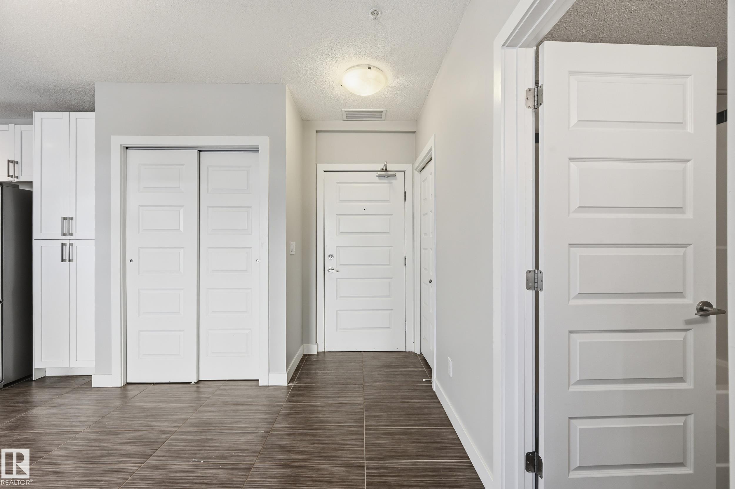 Hall with a textured ceiling and baseboards - 511 5151 Windermere Boulevard, Edmonton, AB - Indoor Photo Showing Other Room