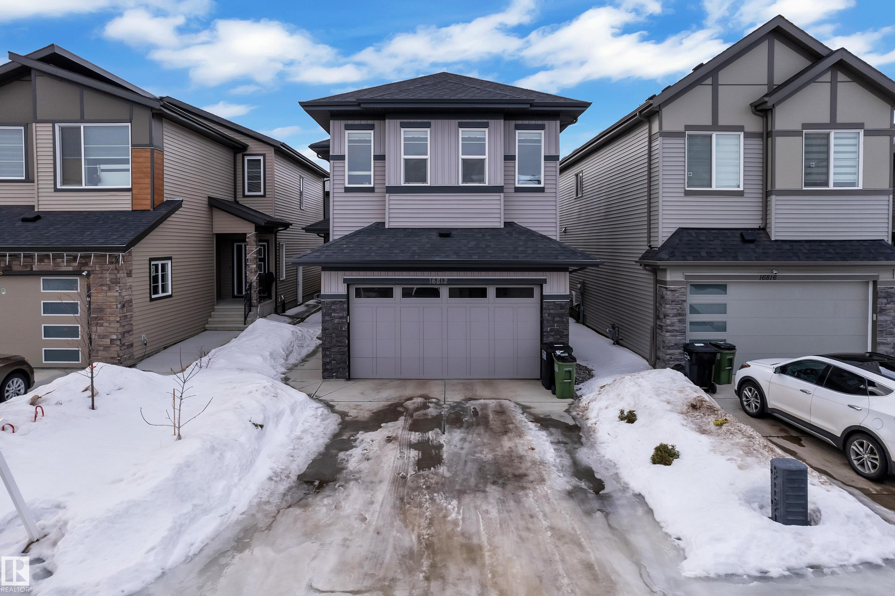 View of front facade featuring stone siding, roof with shingles, and driveway - 16812 48 Street Nw, Edmonton, AB - Outdoor With Facade