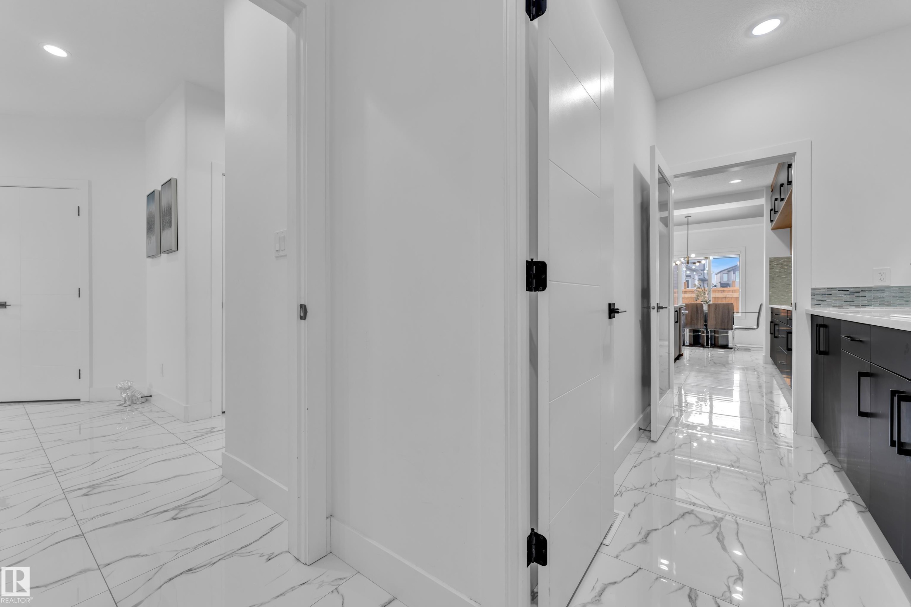 Corridor with hanging lights and light marble finish flooring - 16812 48 Street Nw, Edmonton, AB - Indoor Photo Showing Other Room