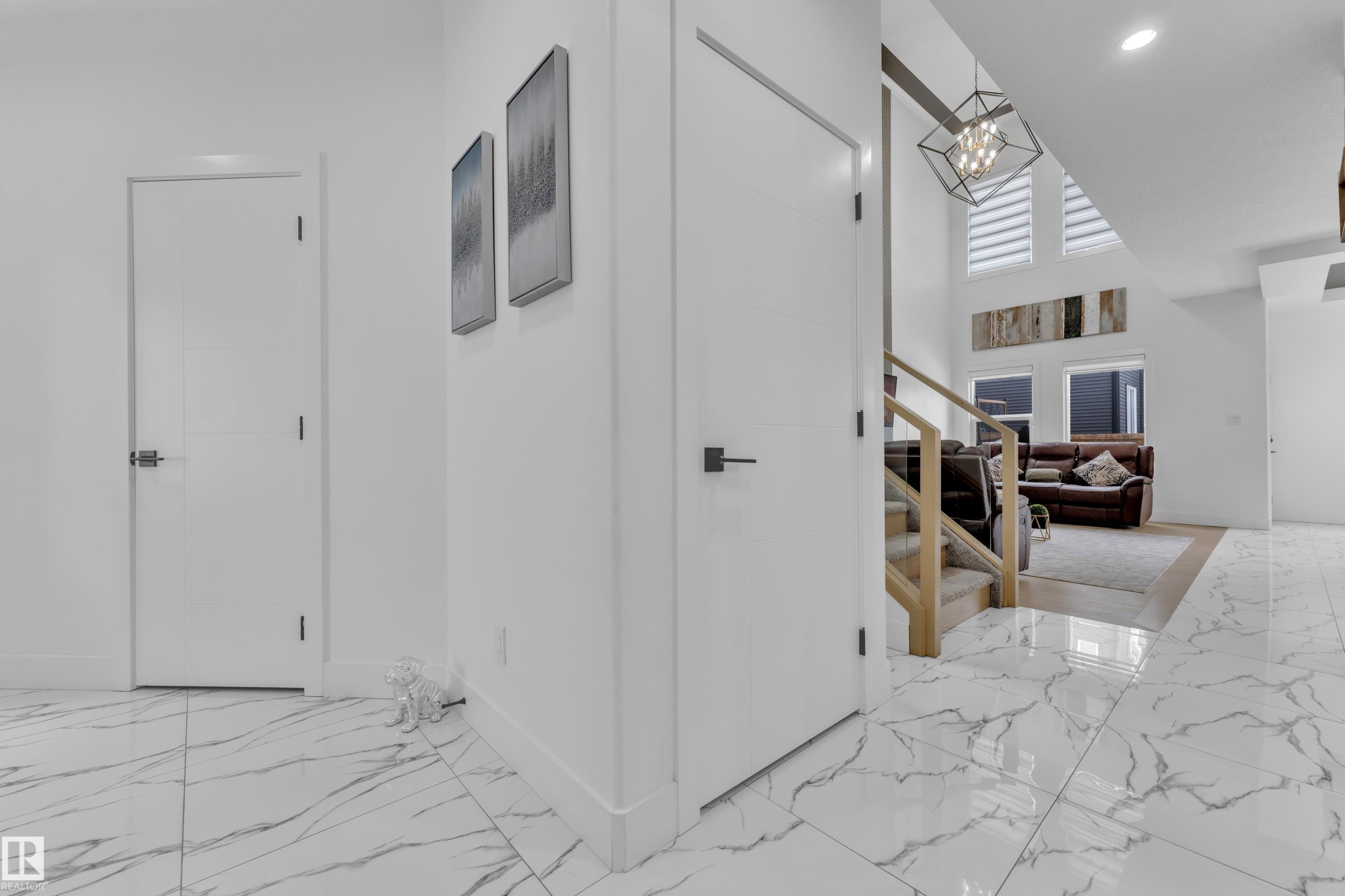 Hallway featuring light marble finish flooring, a high ceiling, and hanging lights - 16812 48 Street Nw, Edmonton, AB - Indoor Photo Showing Other Room