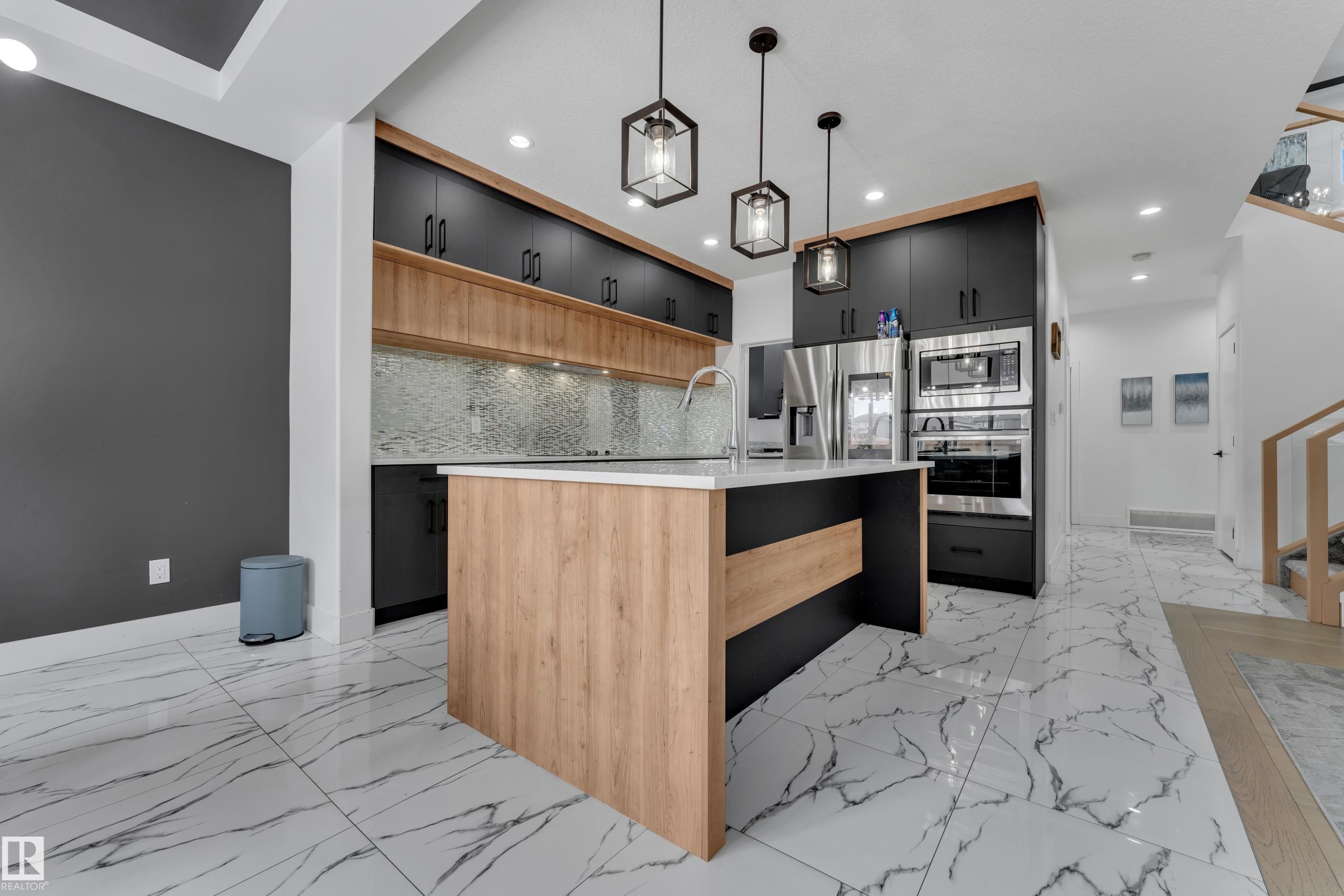 Dual tone kitchen featuring two tone color scheme, an island with sink, modern cabinets, stainless steel appliances, and pendant lighting - 16812 48 Street Nw, Edmonton, AB - Indoor Photo Showing Kitchen