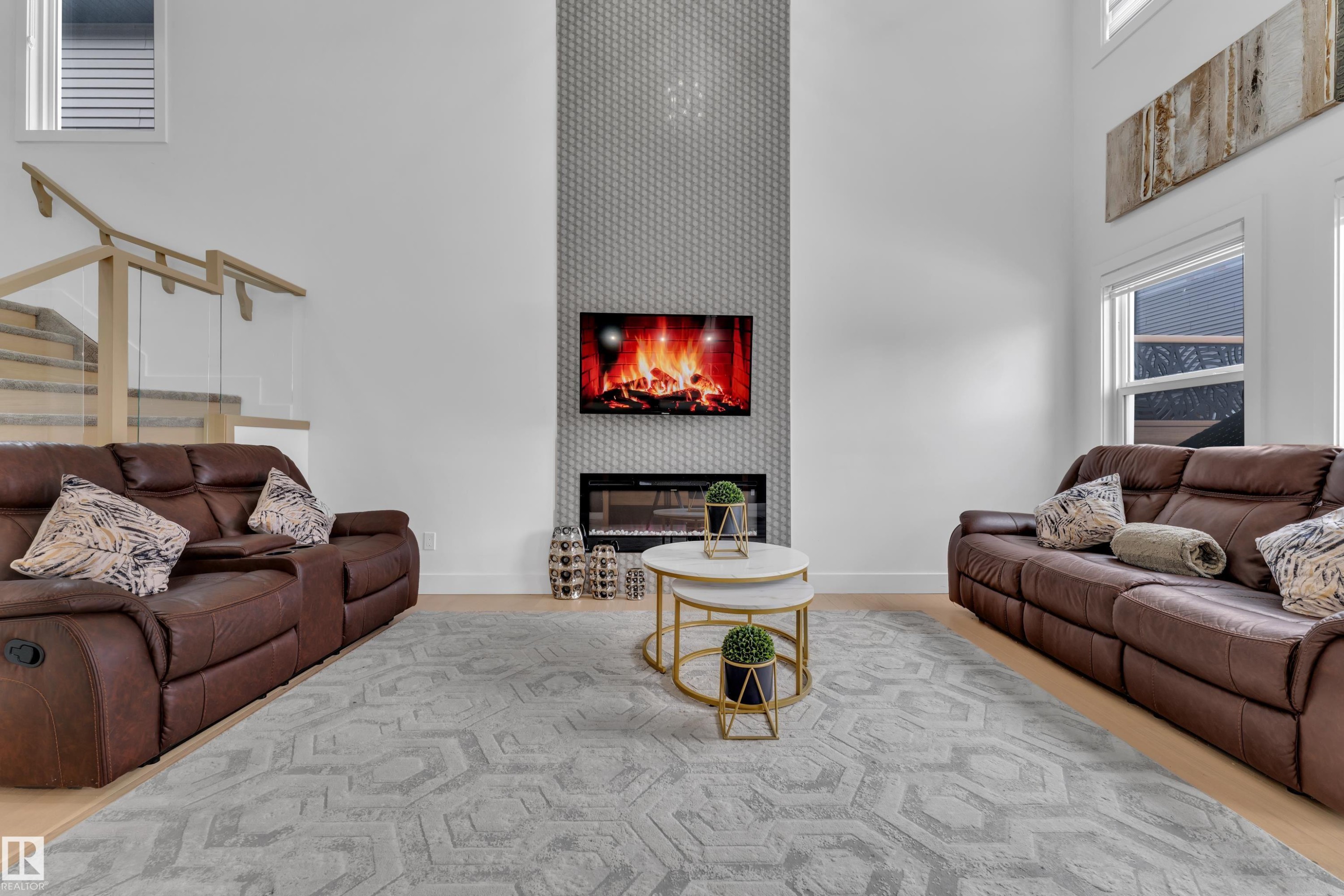 Living area with a high ceiling and a glass covered fireplace - 16812 48 Street Nw, Edmonton, AB - Indoor Photo Showing Living Room With Fireplace