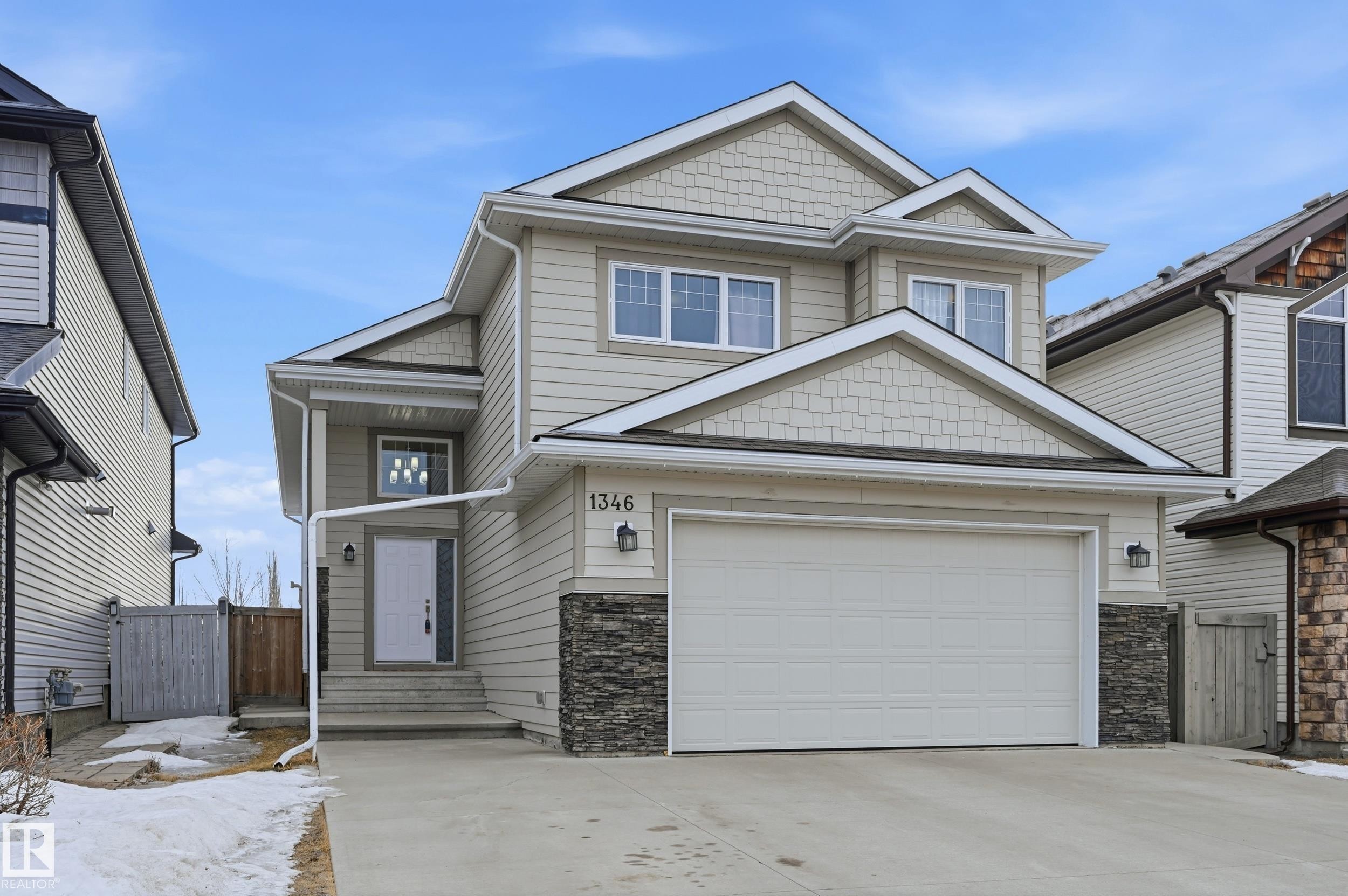 Craftsman-style house featuring a gate, stone siding, and driveway - 1346 Cunningham Drive W, Edmonton, AB - Outdoor With Facade