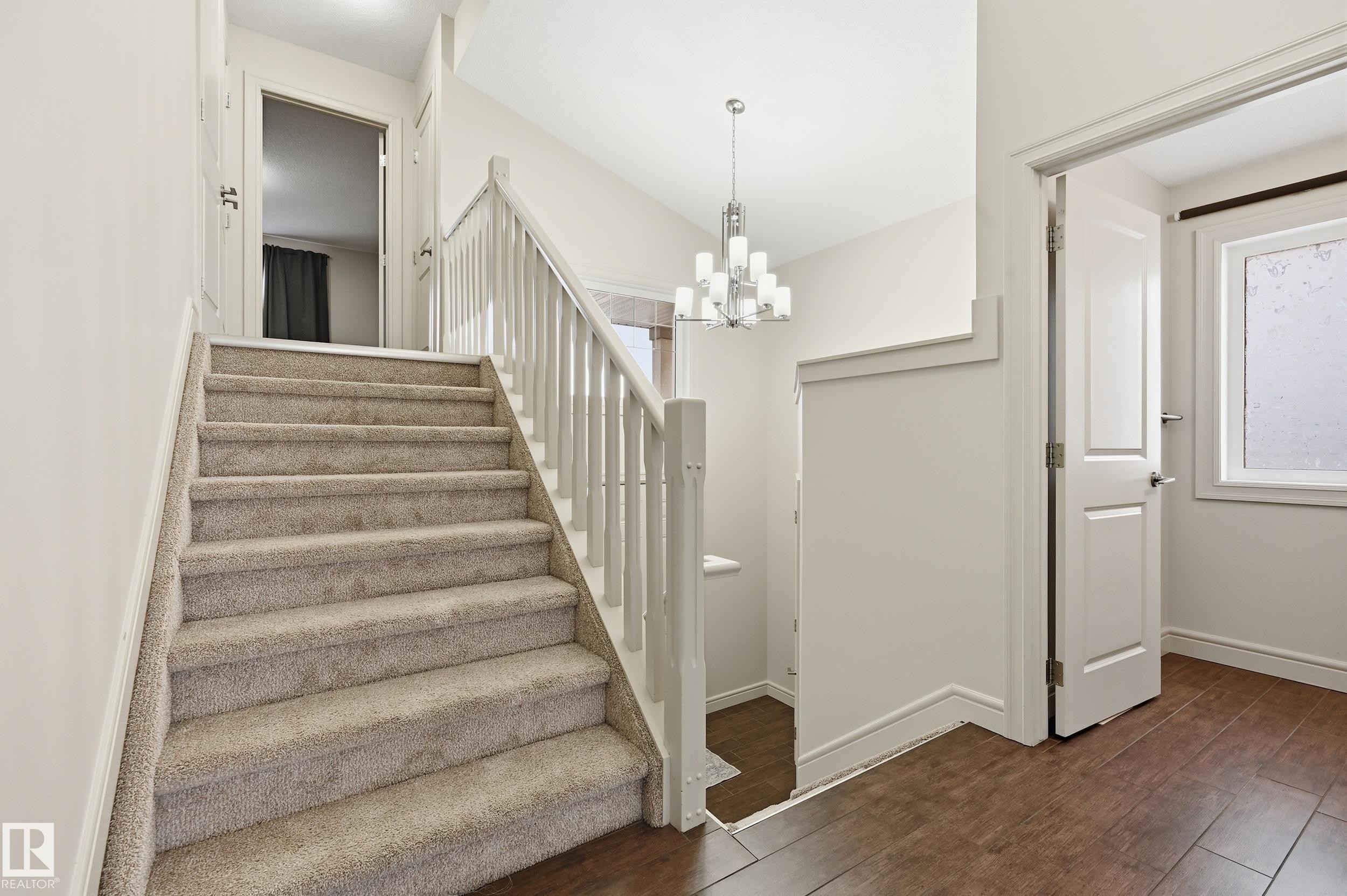 Stairway with wood-type flooring and suspended lighting - 1346 Cunningham Drive W, Edmonton, AB - Indoor Photo Showing Other Room