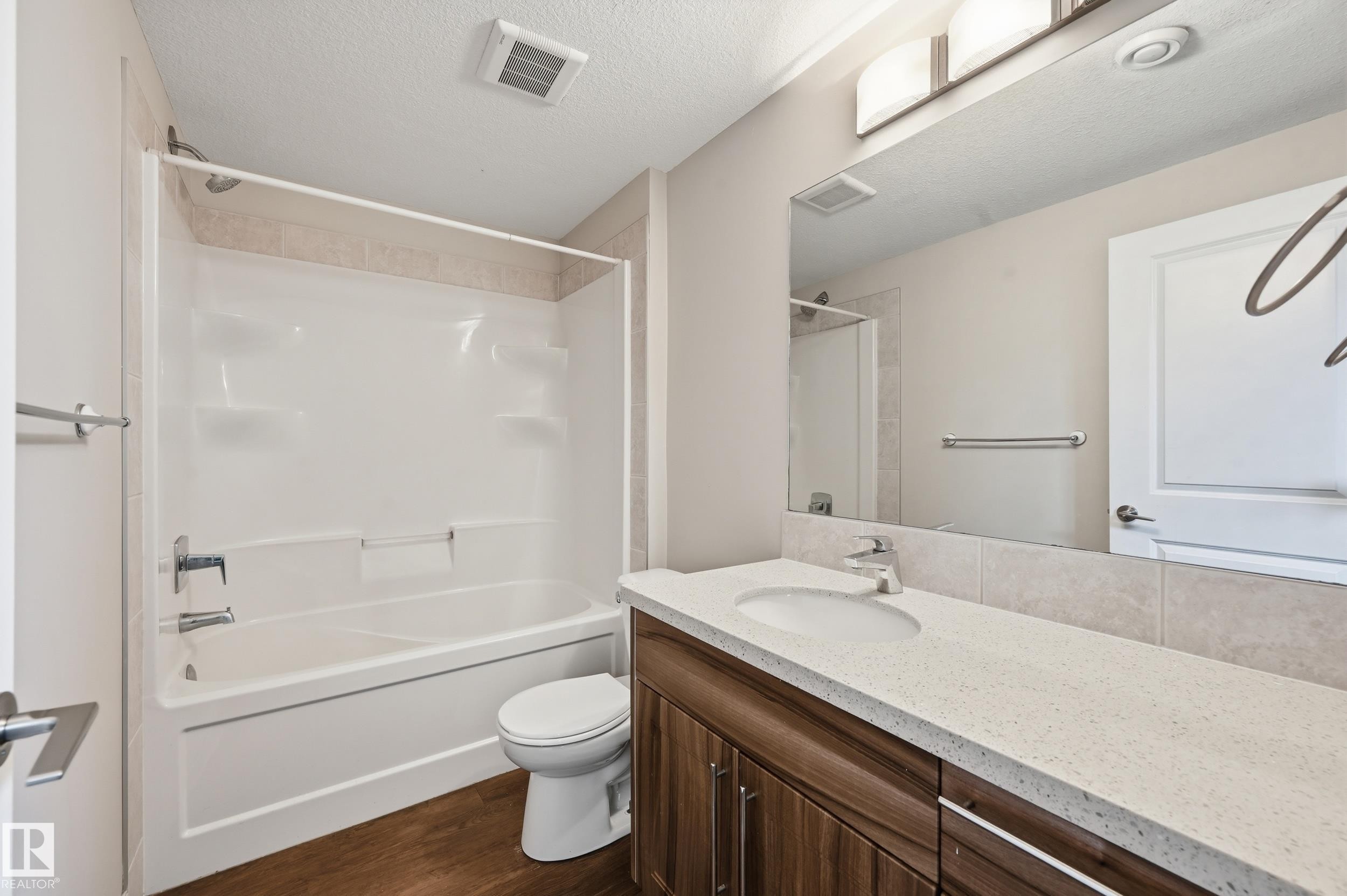 Full bath with vanity, a textured ceiling, shower combination, and dark wood-type flooring - 1346 Cunningham Drive W, Edmonton, AB - Indoor Photo Showing Bathroom
