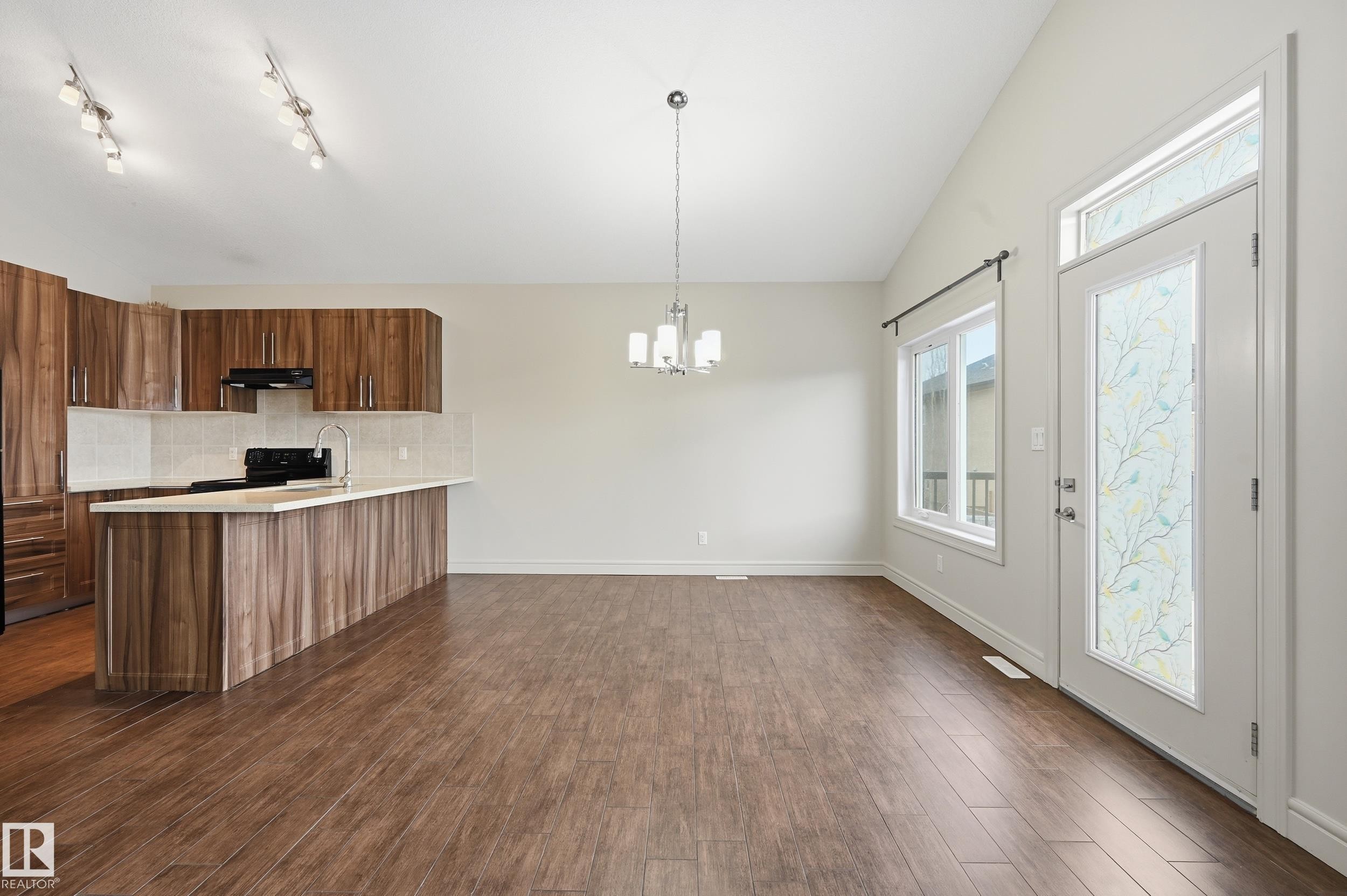 Kitchen with a peninsula, tasteful backsplash, black electric range oven, dark wood-style flooring, and hanging lights - 1346 Cunningham Drive W, Edmonton, AB - Indoor Photo Showing Kitchen
