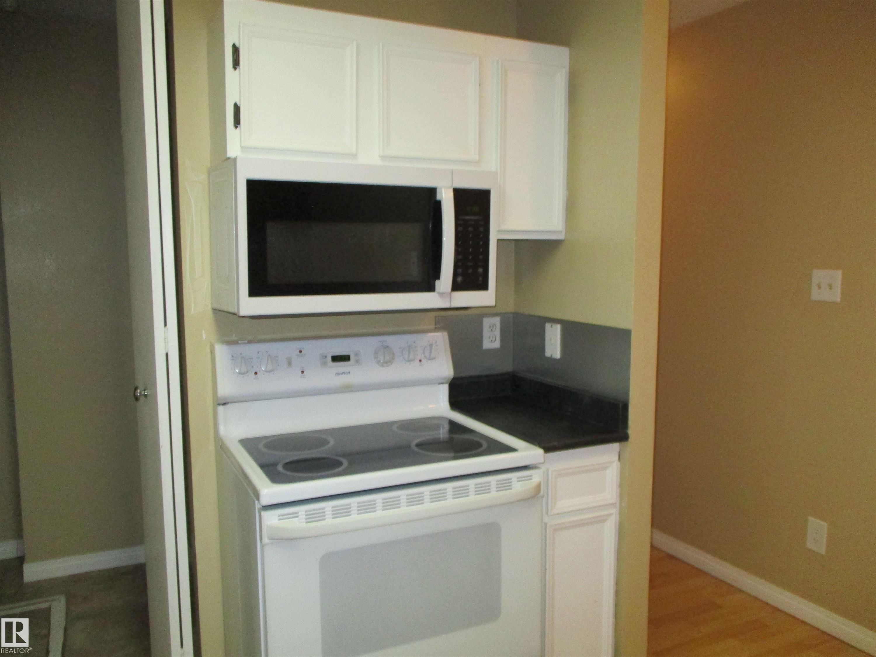 Kitchen with white appliances, white cabinets, dark countertops, and light wood-type flooring - 1186 Saddleback Road, Edmonton, AB - Indoor Photo Showing Kitchen